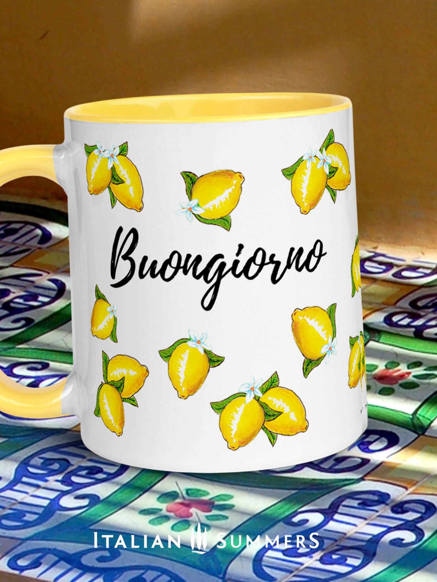 Italy inspired coffee mug with happy sketched lemons  over the whole mug on all sidesand a playful Buongiorno writing beteen the lemons. The inside and handle of the mug are yellow. On the lemons are little lemon flowers. Made by Italian Summers
