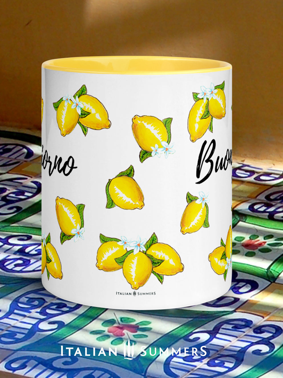 Italy inspired coffee mug with happy sketched lemons over the whole mug on all sidesand a playful Buongiorno writing beteen the lemons. The inside and handle of the mug are yellow. On the lemons are little lemon flowers. Made by Italian Summers