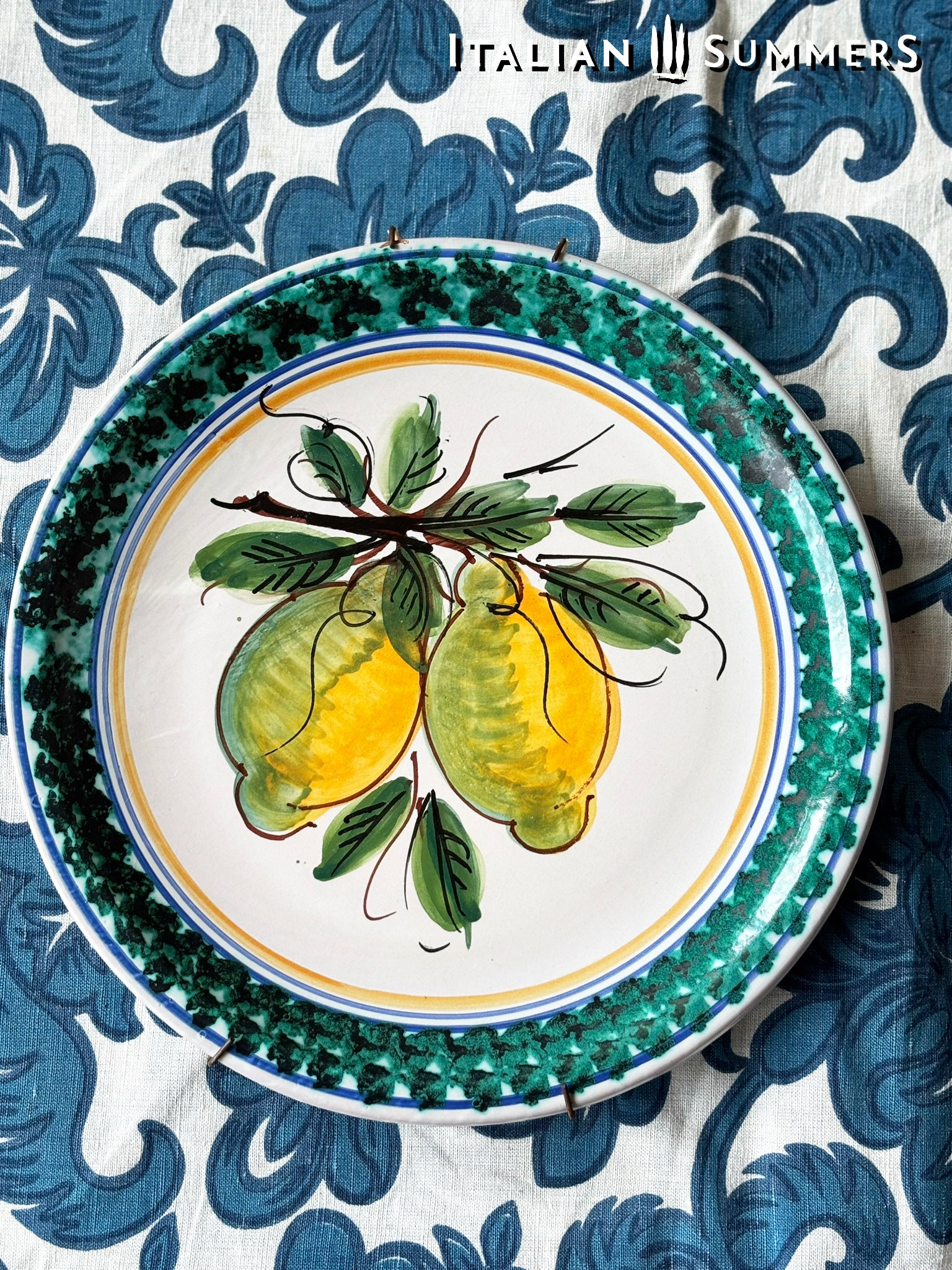 Vintage Sicilian Caltagirone maiolica Ceramic plate with lemon design on a blue and white patterned background, featuring 'Italian Summers' branding.