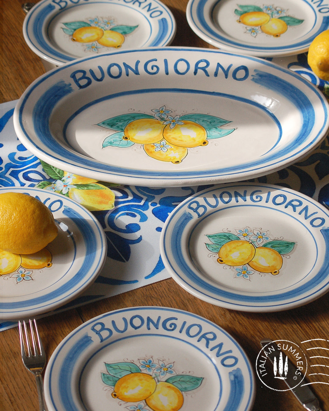 Ceramic plate Buongiorno Limoni handpainted in Sicily. This  plate has the quote Biongiorno on the rim - handpainted  - And colorfull lemons on the center of the plate  with lemon flowers. On the rim of the plate there are blue paint stripes. The blue color is ultra marine. This plate is designed and sold by Italian Summers.