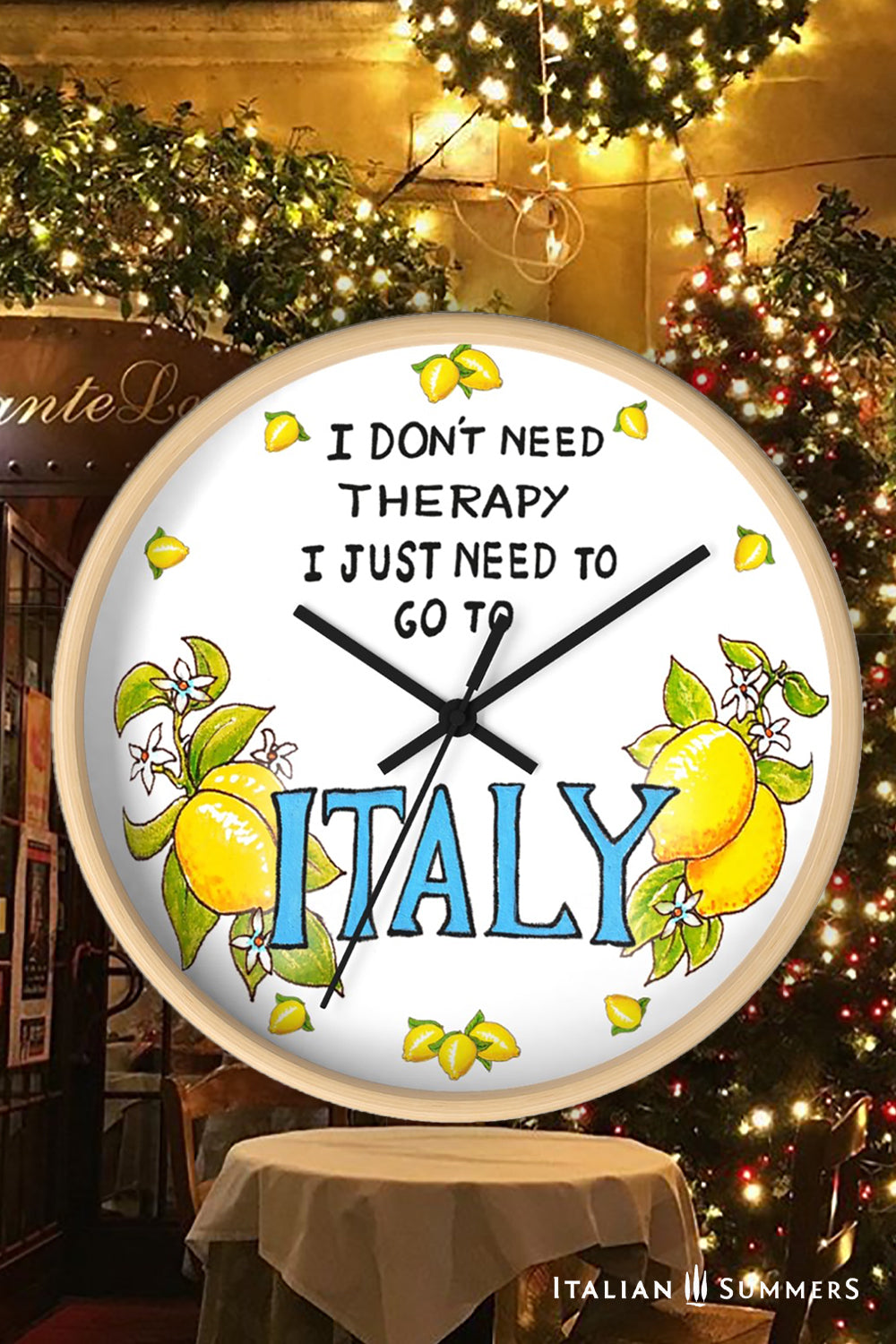 Italy inspired wall clock with the quote "I don't need therapy, I just need to go to Italy" . The quote is in the top center of the clock in balck handriting. In the lower part of the clock there is Italy written in big blue letter with on both sides a bundle of lemons with flowers. In stead of numbers there are little lemons. The body if the clock is available in wood color and white. The hands color is available in white and black. Made by Italian Summers.