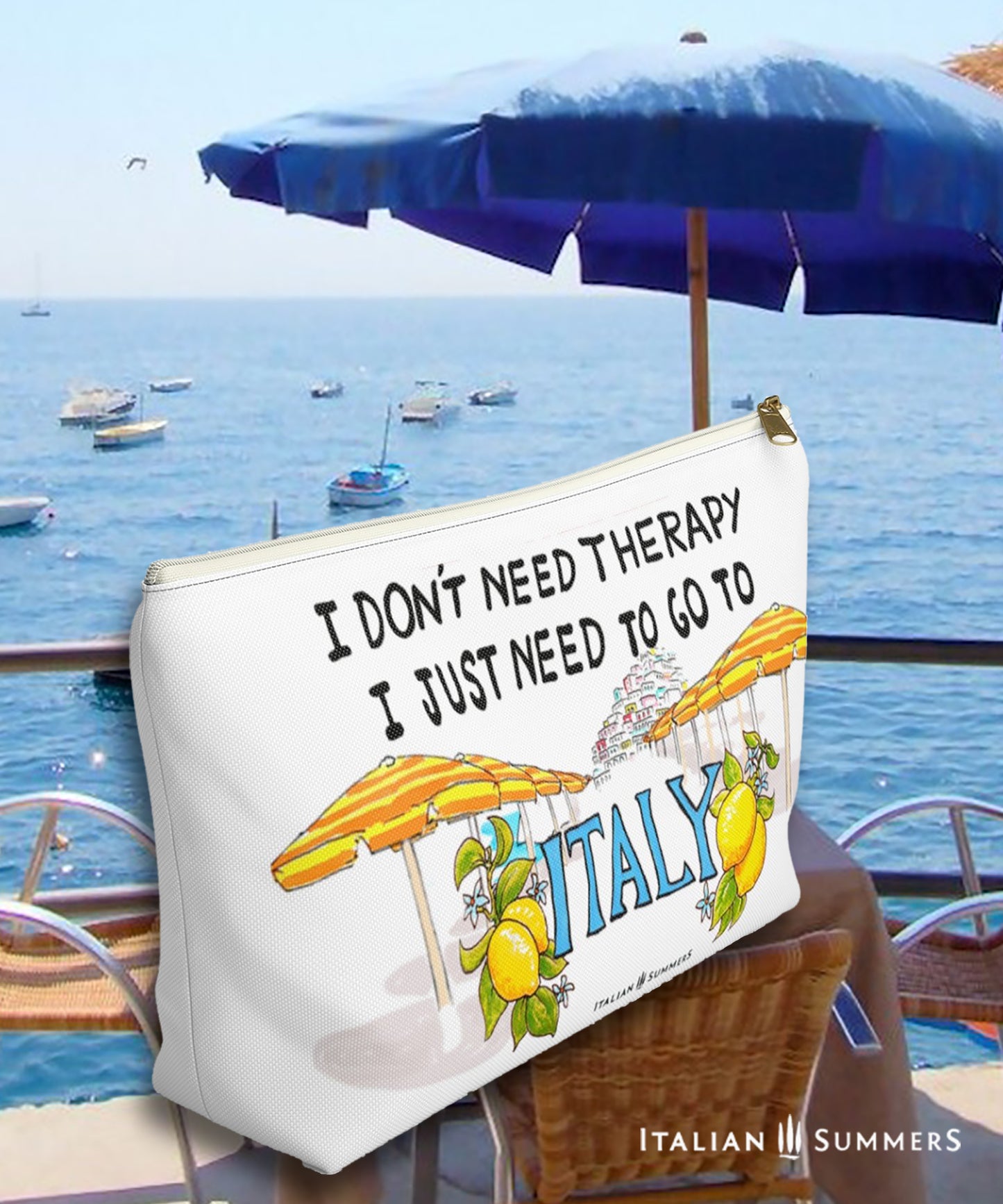 Italy inspired clutch of white canvas with he quote I don't need therapy, I just need to go to Italy. On the clutch there is a sketch of the beach umbrellas on Positano beach The beach umbrellas are yellow and orange striped. In the distance you ccan see the stagered houses of Positano. The word Italy in in big blue letters and is flancked with lemons. Designed by Italian Summers.