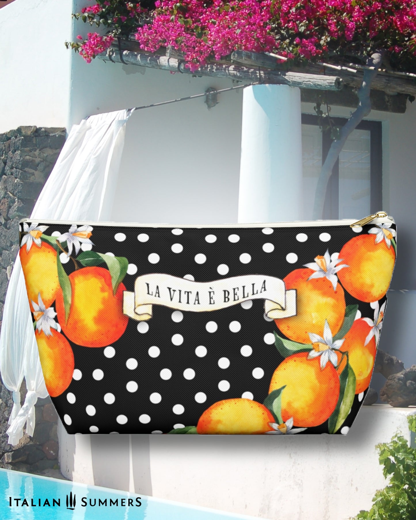 Made to order zippered canvas clutch printed with Sicilian oranges an blooms on a black field with white polka dots. a scroll on th front has the text LA VITA E BELLA.