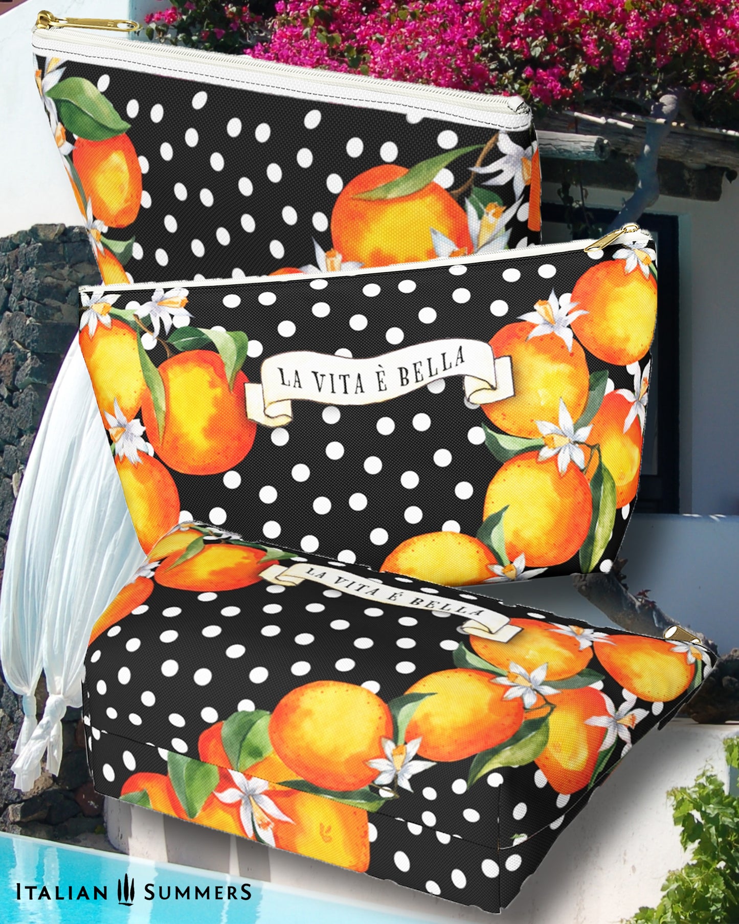 Made to order zippered canvas clutch printed with Sicilian oranges an blooms on a black field with white polka dots. a scroll on th front has the text LA VITA E BELLA.