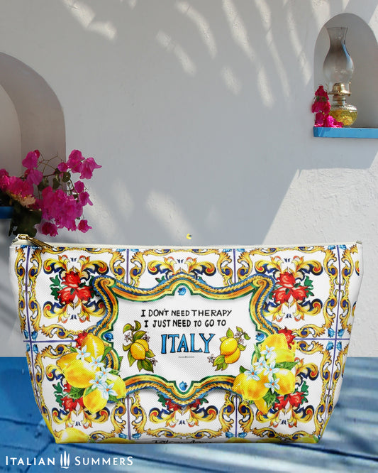 Italy, Sicily inspired clutch with the quote I don't need therapy, I just need to go to Italy. Next to the word Italy are on both sides Sorrento lemons. The quote is surrounded by Sicilian baroque convolutes and big lemons. On the background there are Sicilian tiles. The bag is printed on two sides and has a white zipper and a t-bottom. Designed by Italian Summers