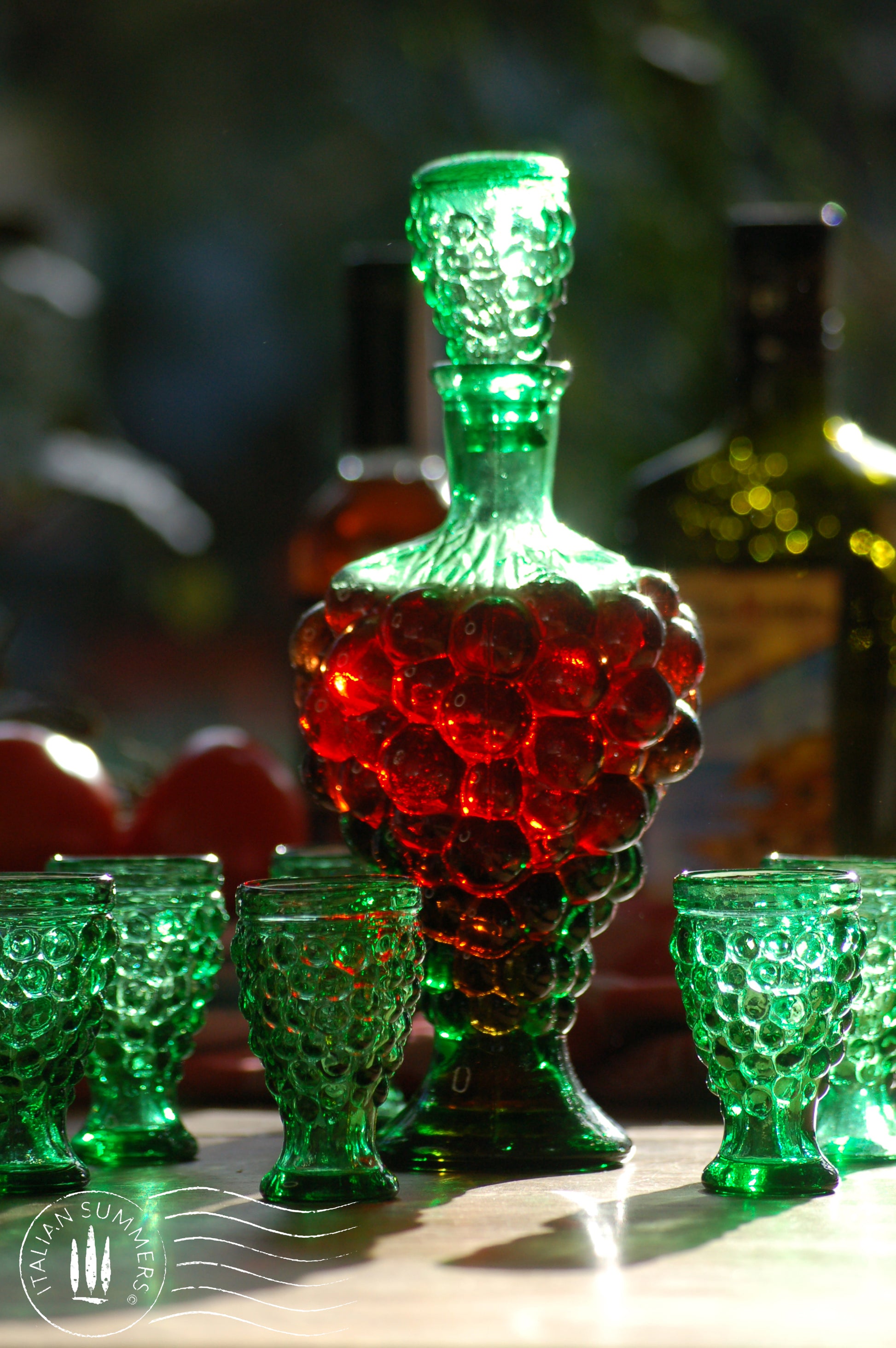 Green glass decanter and goblets with a blurred background