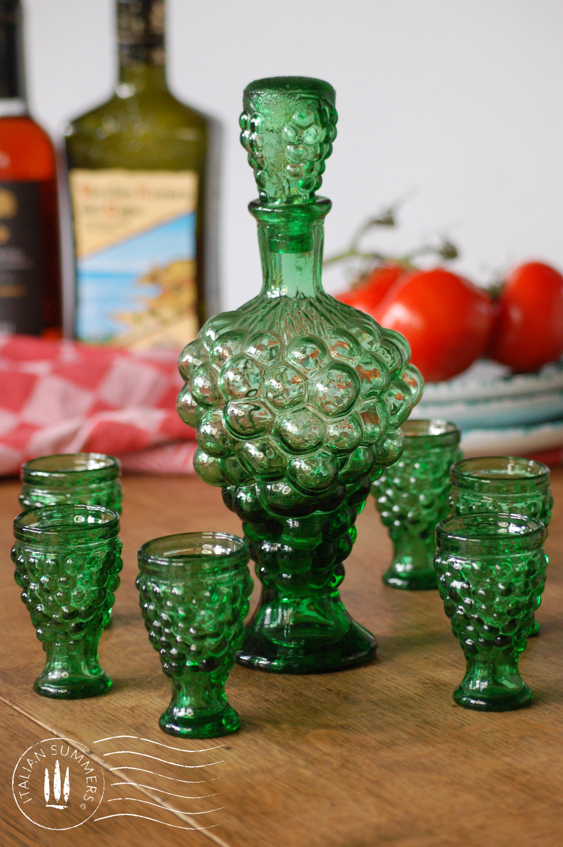 Green glass decanter set with goblets on a wooden surface
