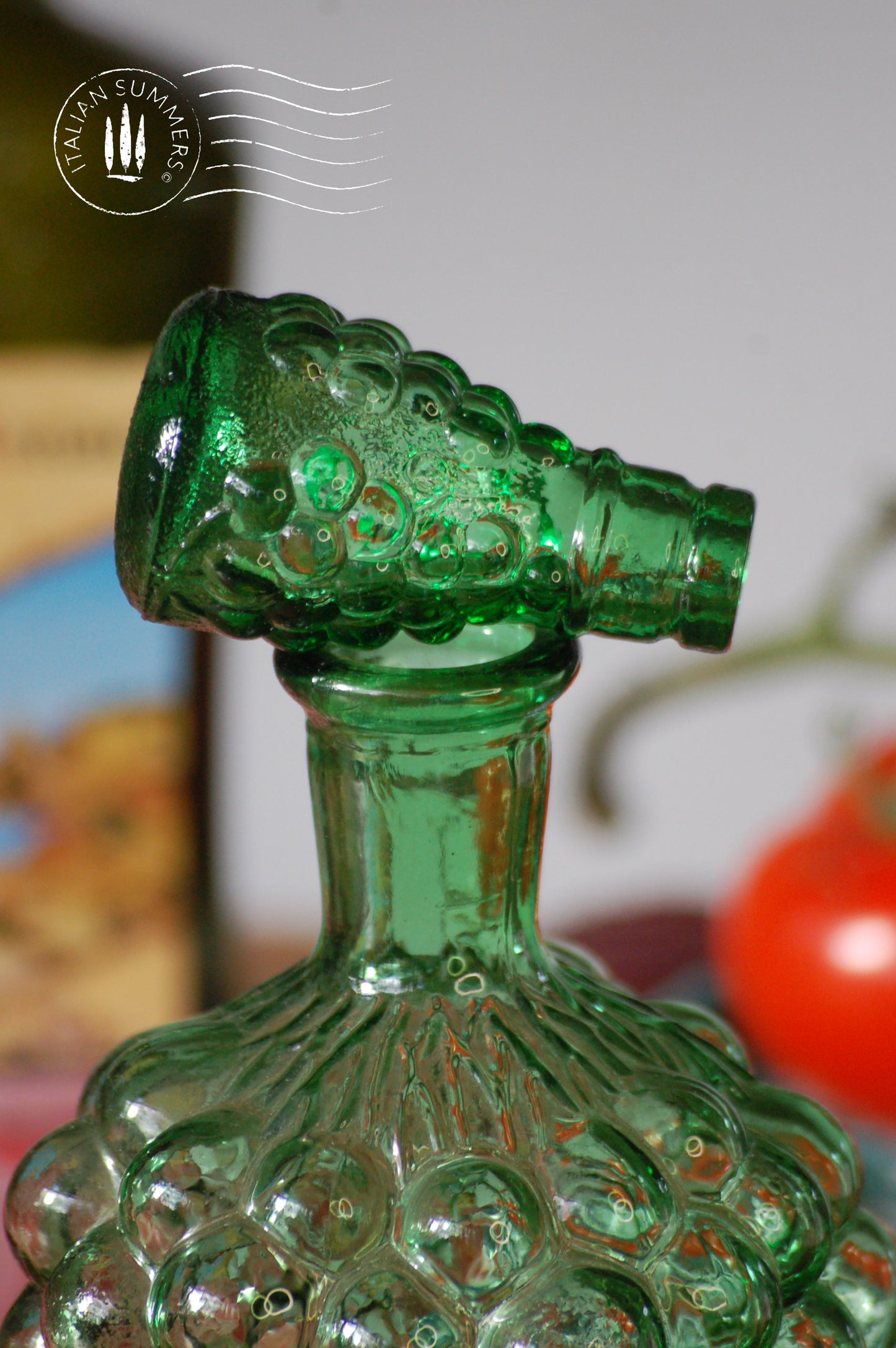 Green glass bottle with decorative neck against a blurred background