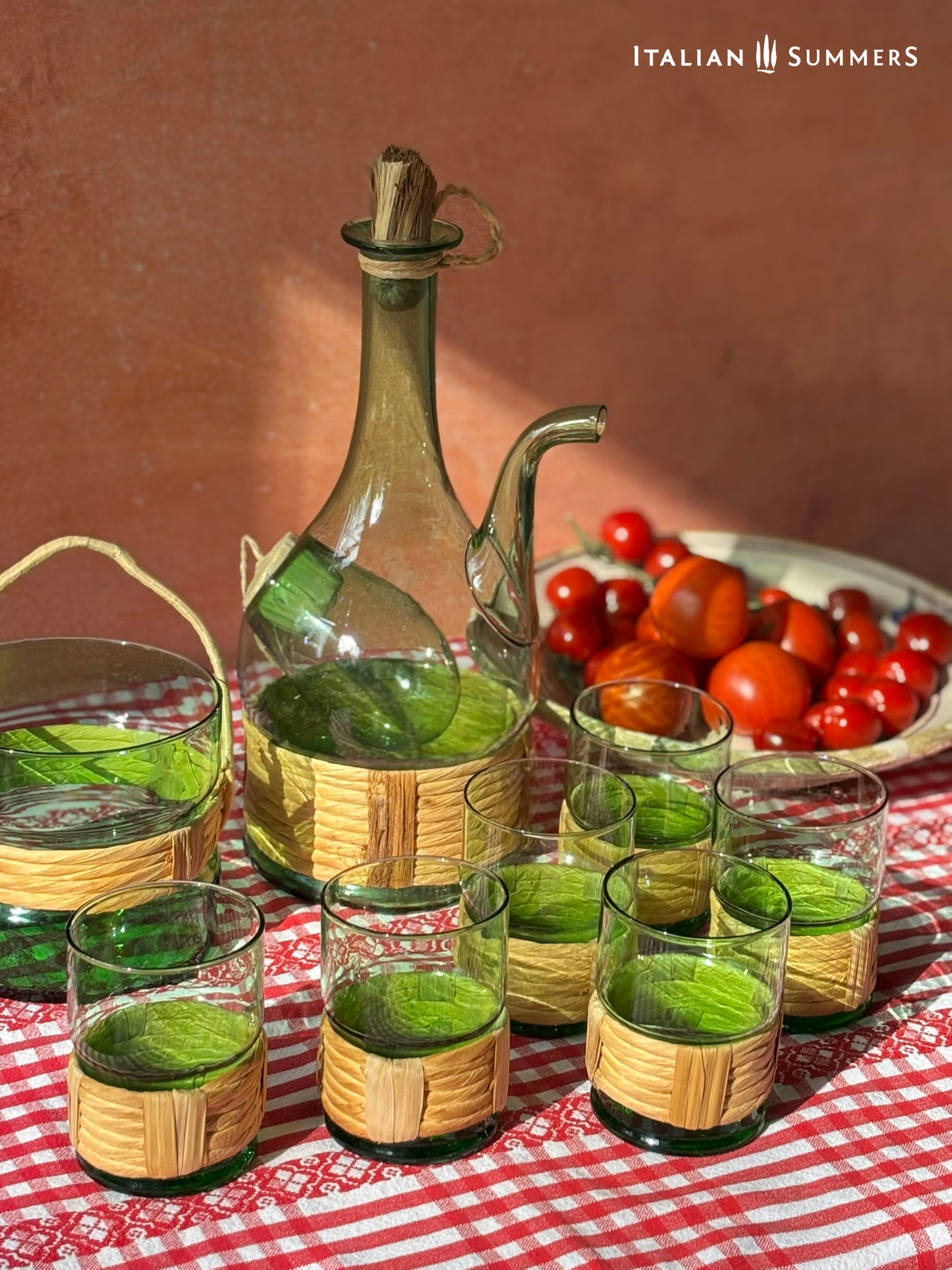 Green Empoli vintage glassware and decanter on a table with a checkered tablecloth, tomatoes, and 'Italian Summers' branding.