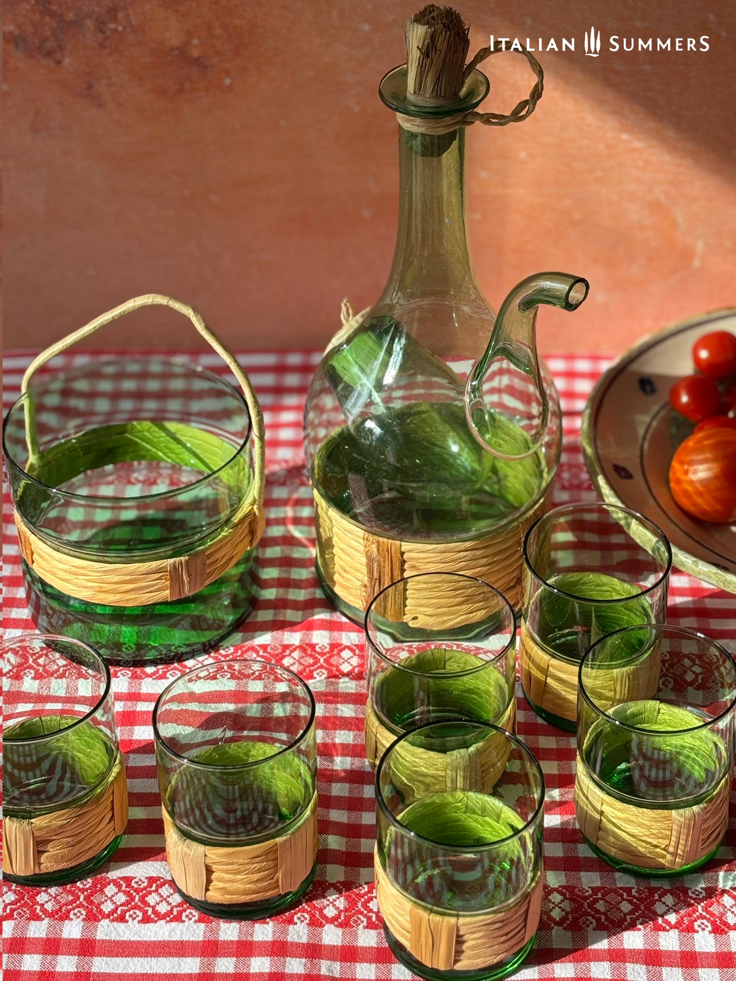 Green Empoli vintage glassware and decanter on a table with a checkered tablecloth, tomatoes, and 'Italian Summers' branding.