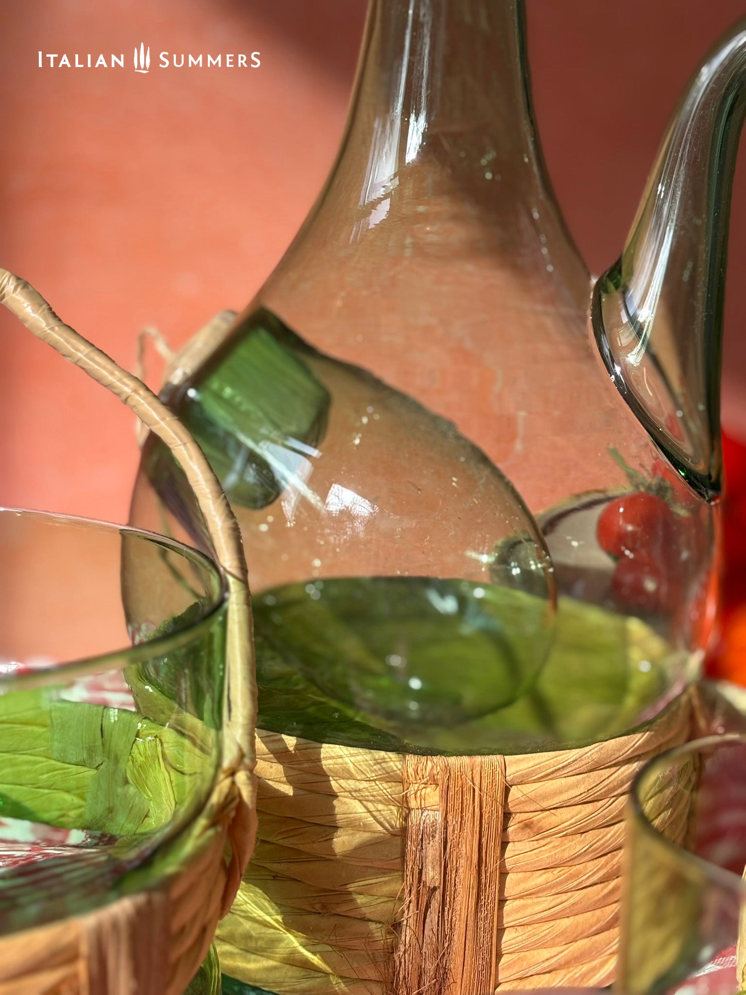 Green Empoli vintage glassware and decanter on a table with a checkered tablecloth, tomatoes, and 'Italian Summers' branding.