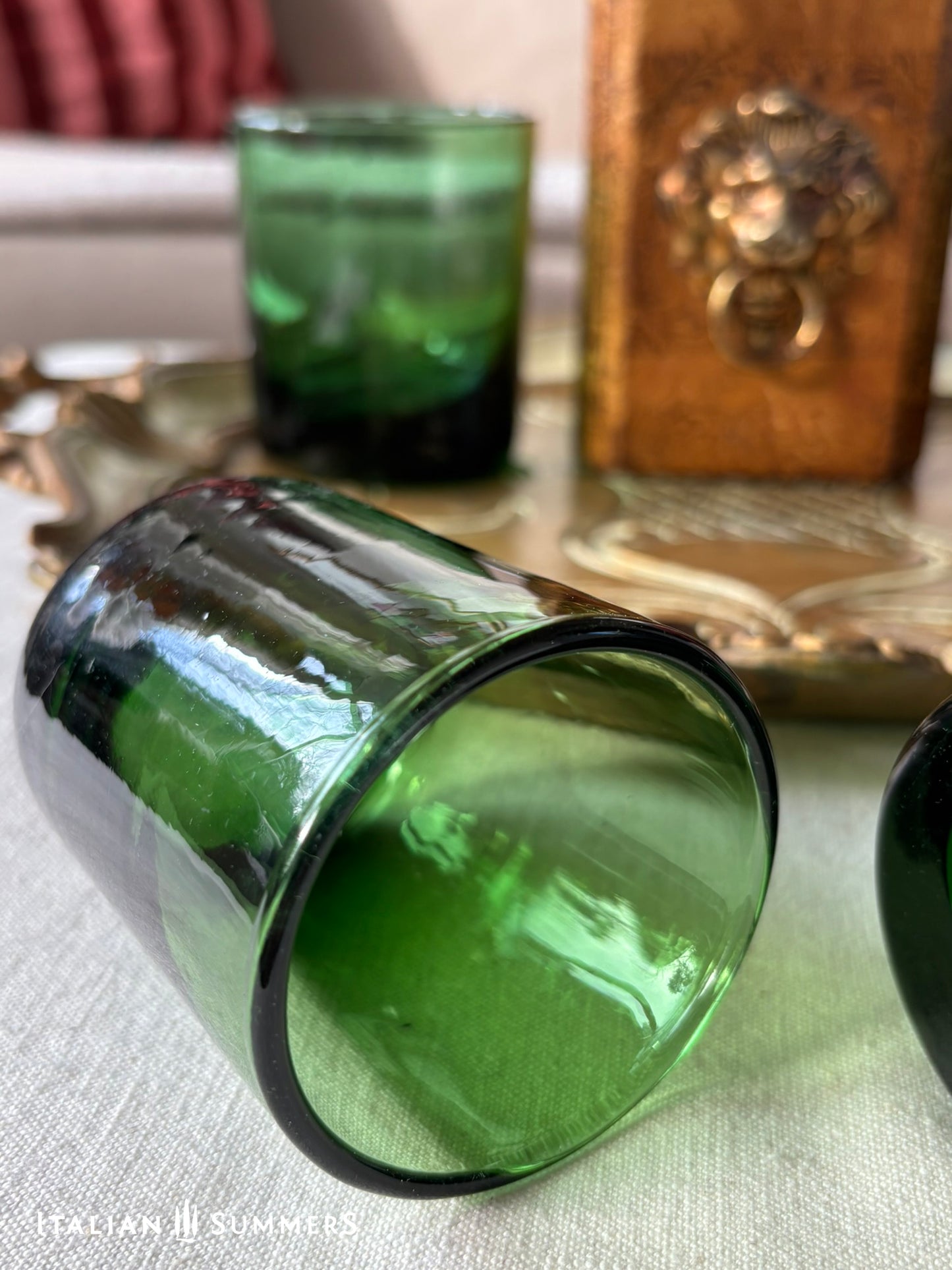 Green glass tumblers on a textured surface with a wooden box in the background.