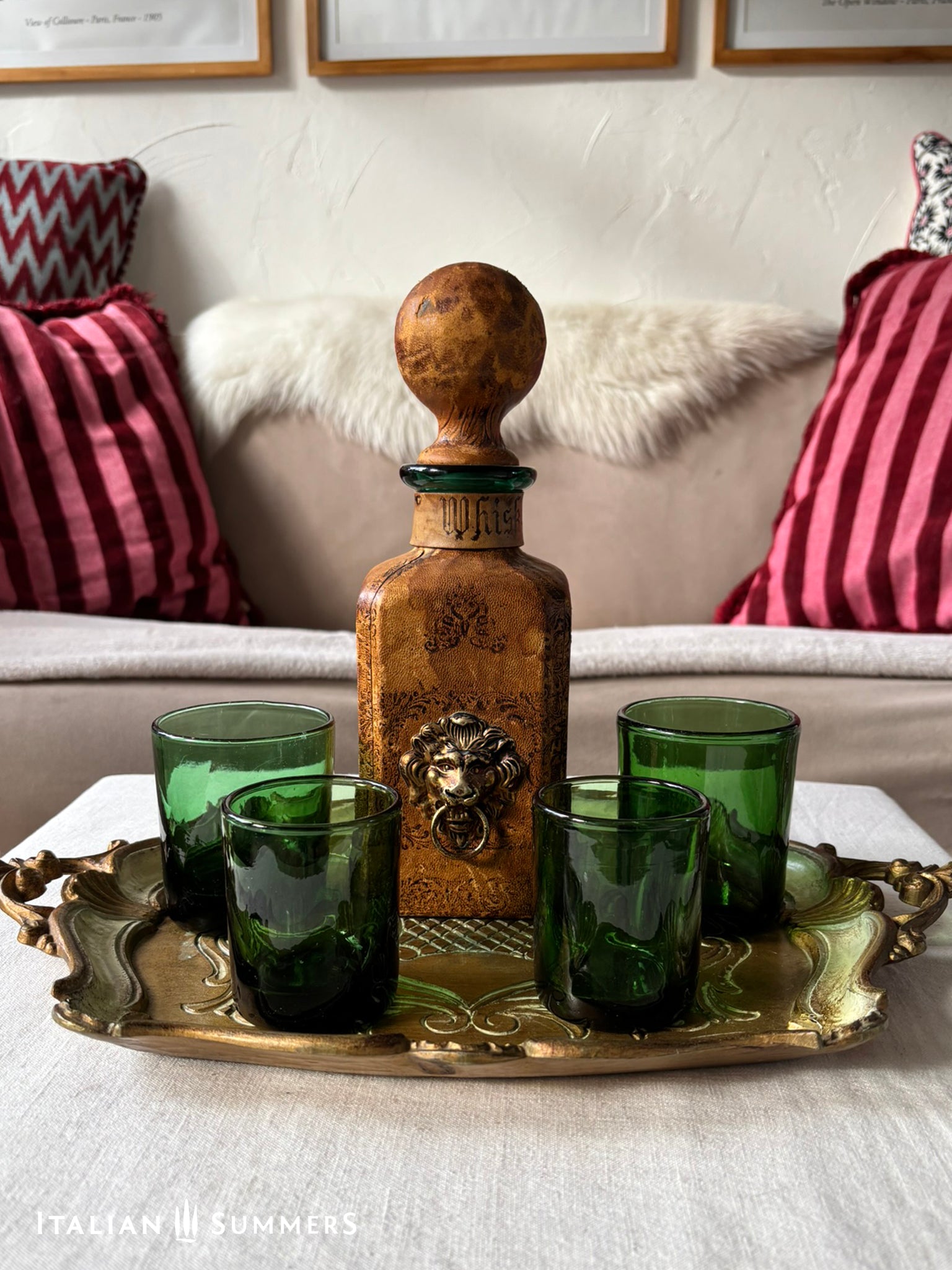 leather-covered decanter with green glasses on a brass tray in a living room setting.