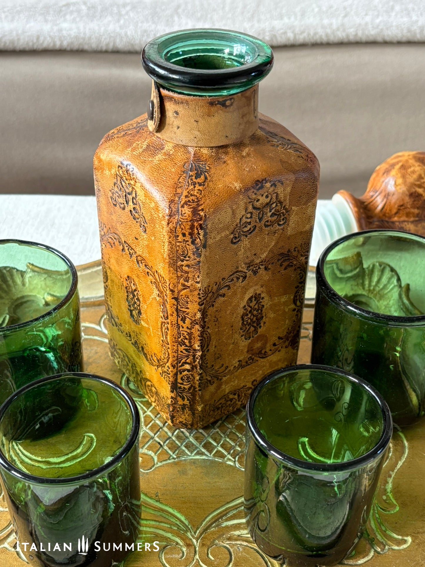 Decorative bottle with green glass on a reflective surface, featuring 'Italian Summers' branding.