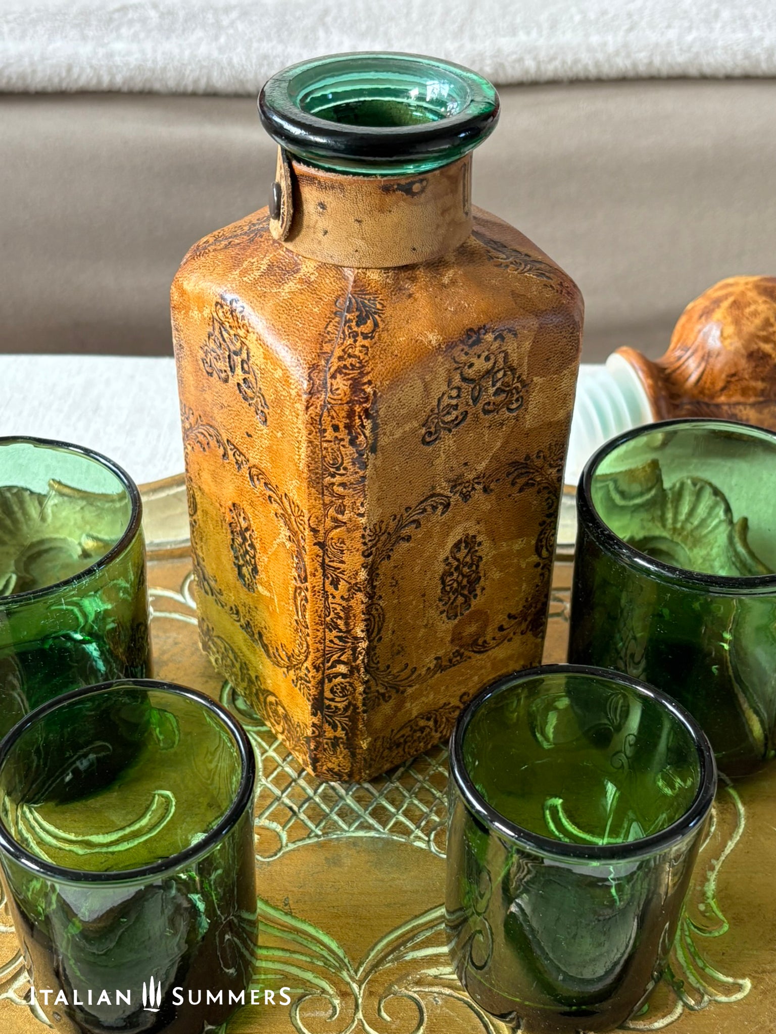 Decorative bottle with green glass on a reflective surface, featuring 'Italian Summers' branding.