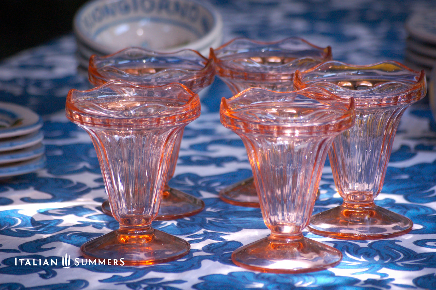 Set of vintage French pink glass dessert coupes  on a blue and white floral patterned tablecloth