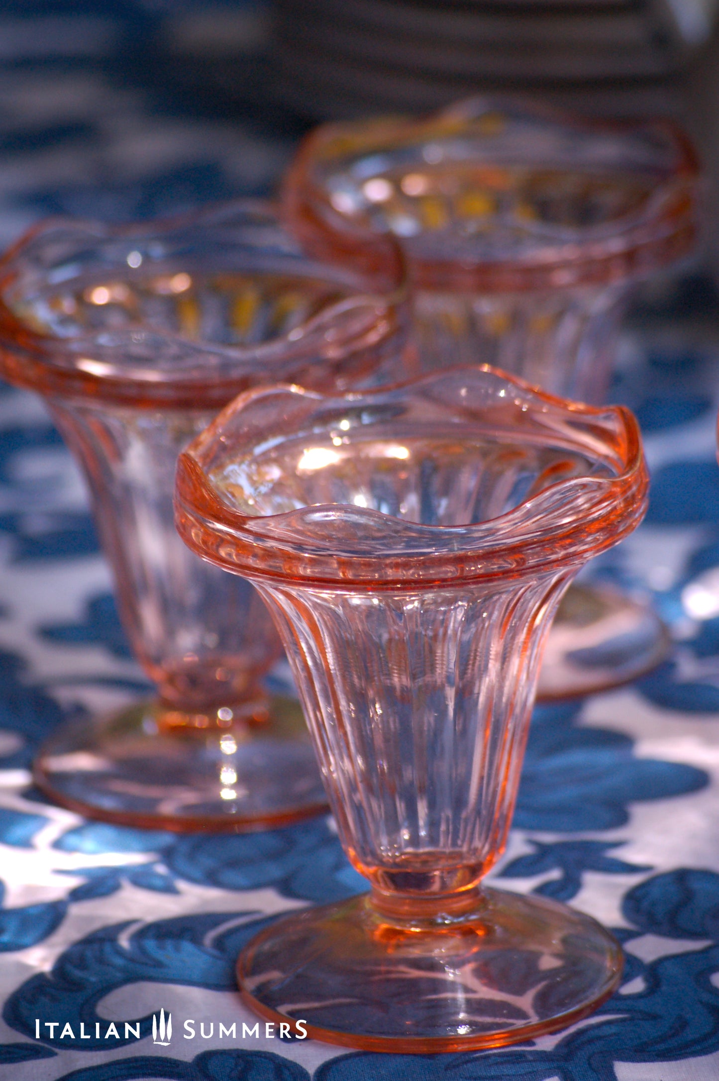 Set of vintage French pink glass dessert coupes  on a blue and white floral patterned tablecloth