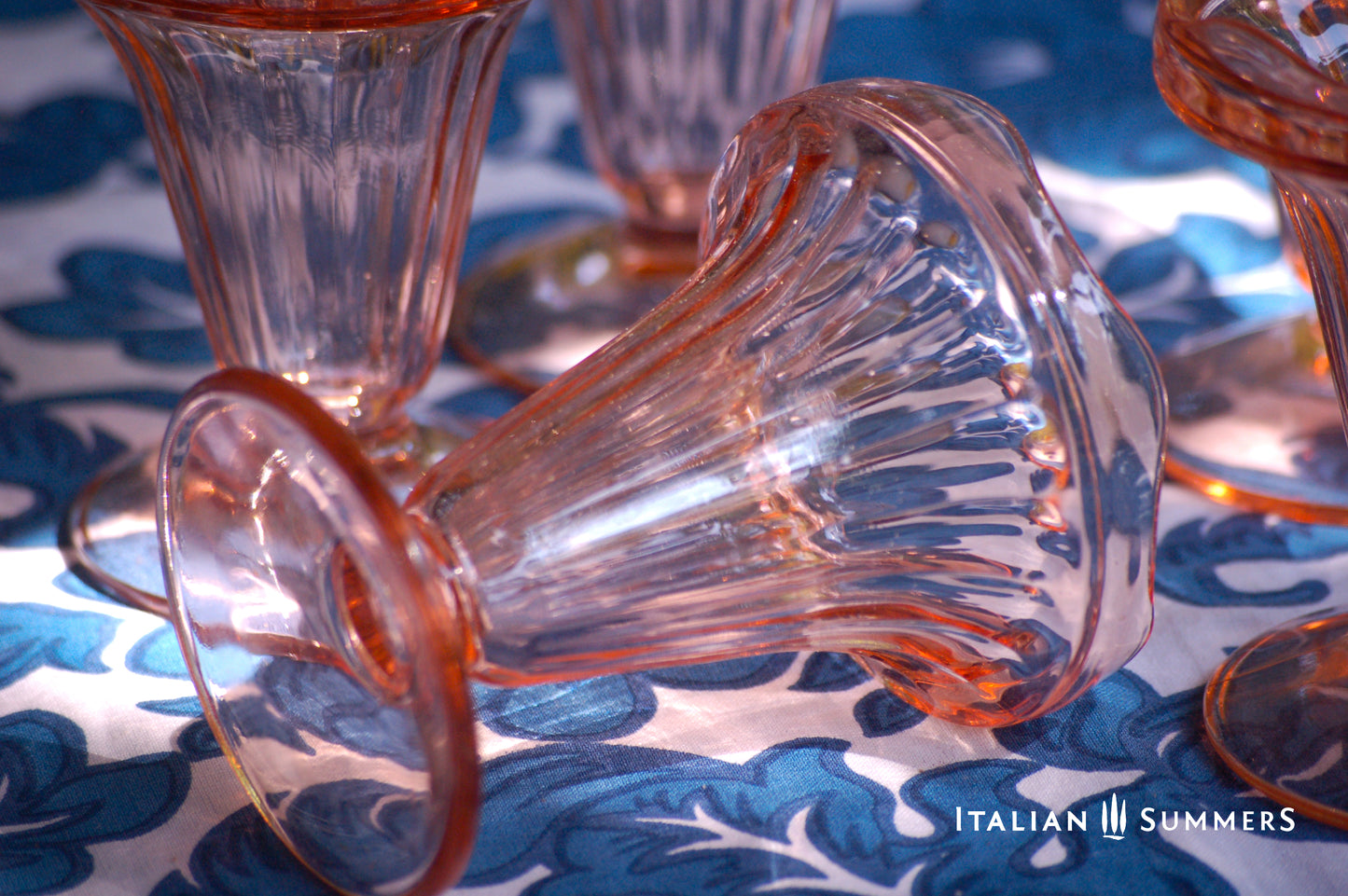 Vintage Pink glass French dessert coupe laying sideways on a blue patterned tablecloth with 'Italian Summers' branding.