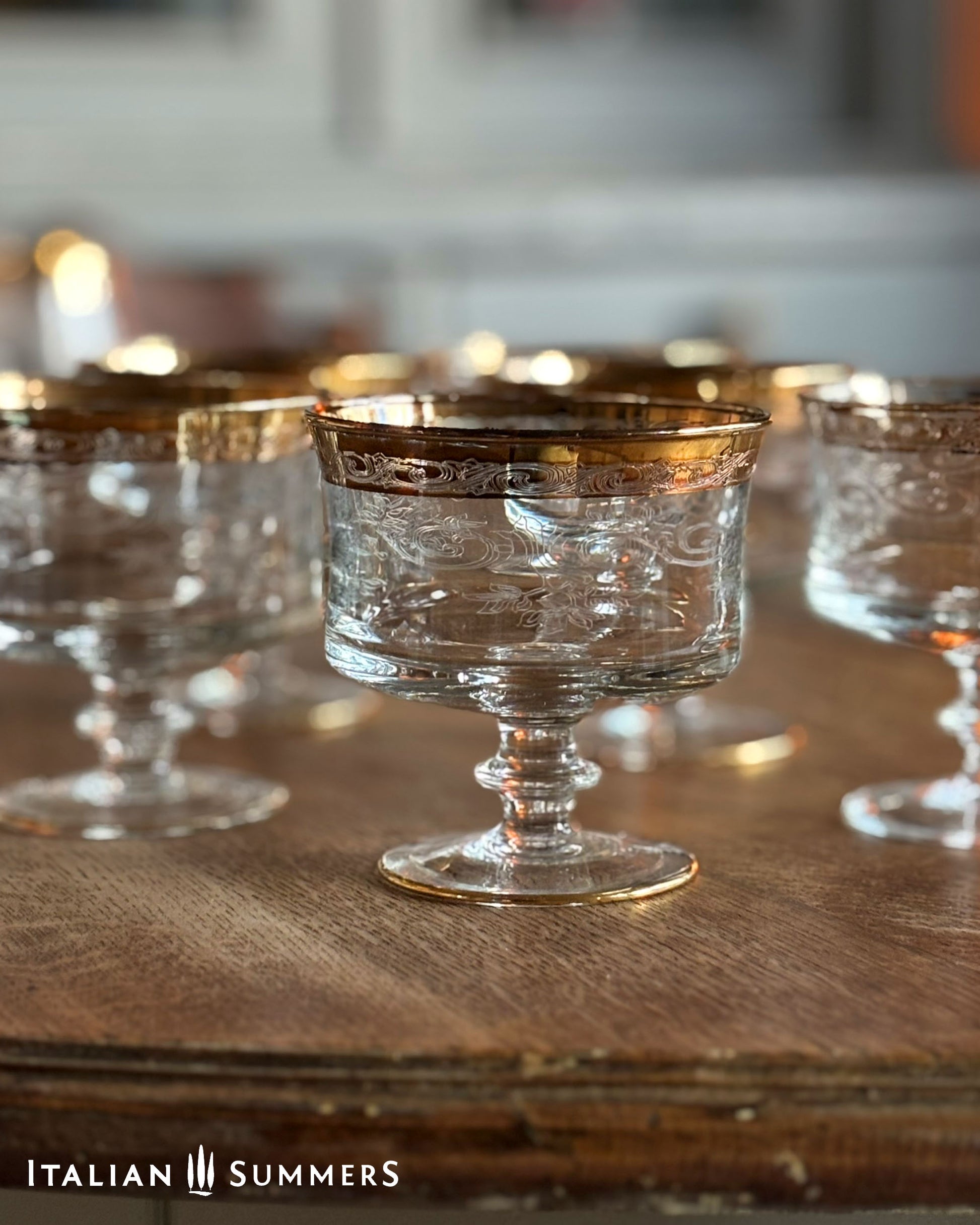 Clear glass goblets with gold rims on a wooden surface, branded 'Italian Summers'.