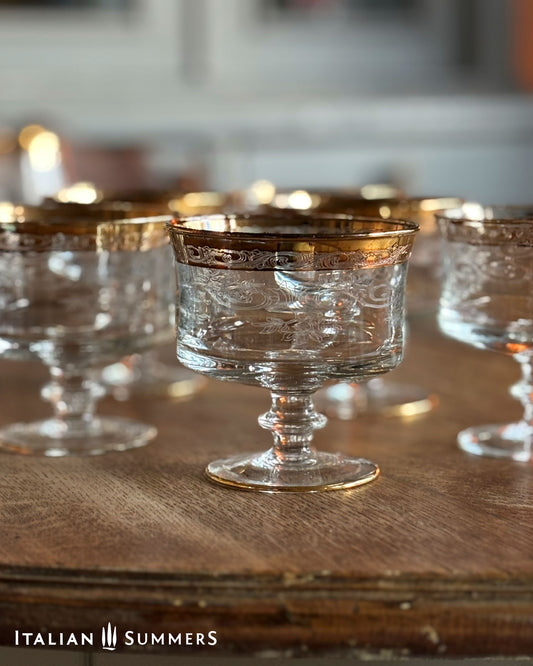 Clear glass goblets with gold rims on a wooden surface, branded 'Italian Summers'.