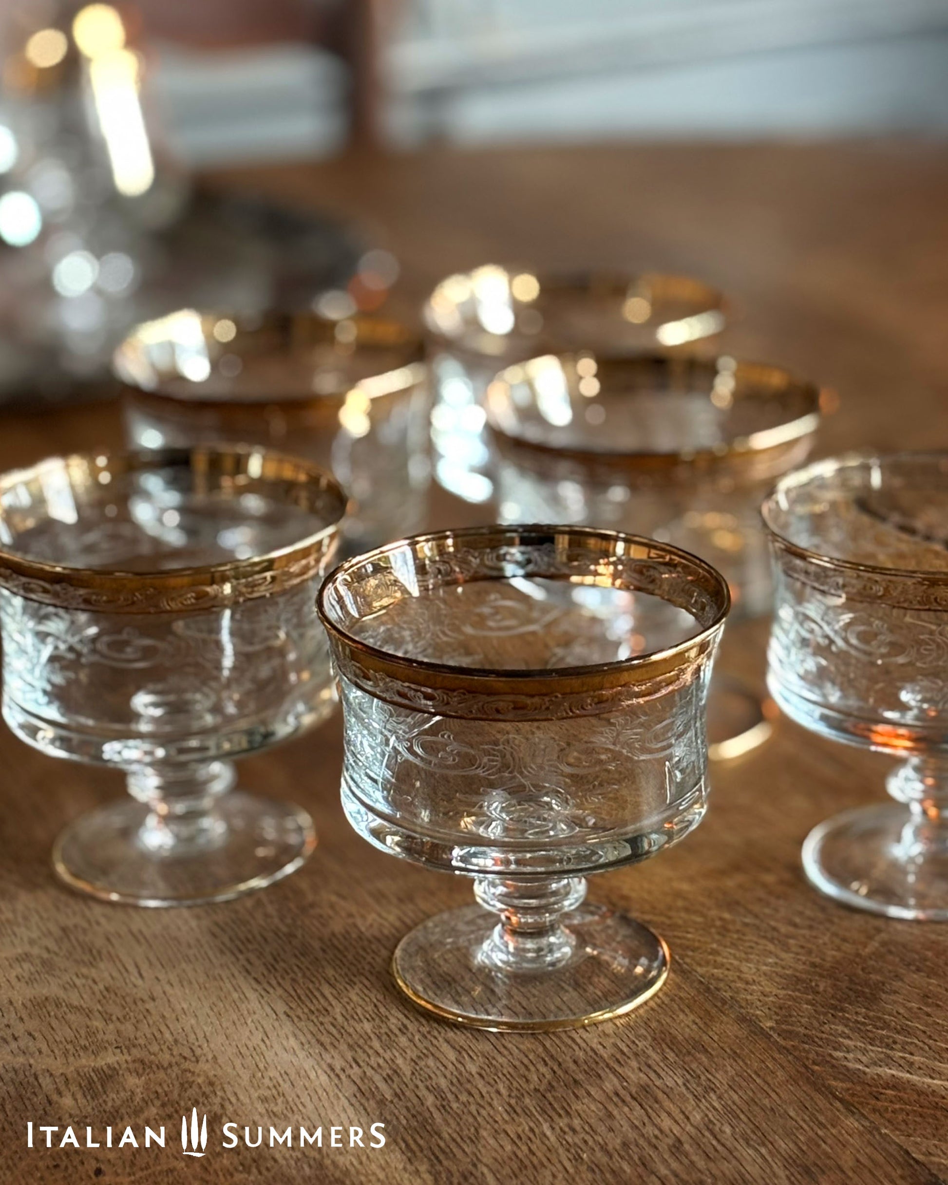 Set of glass dessert dishes with gold rims on a wooden surface, branded 'Italian Summers'.