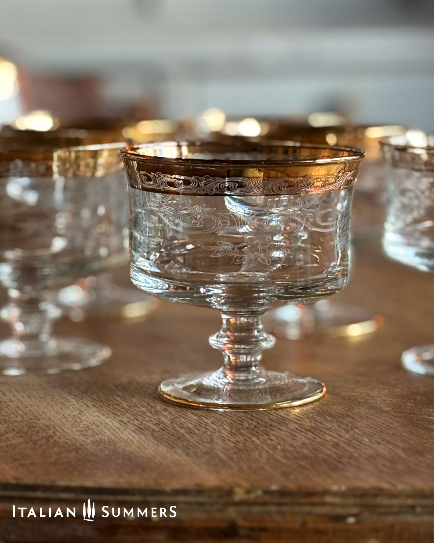 Decorative glass dessert or champagne coupes on a wooden surface with 'Italian Summers' branding.