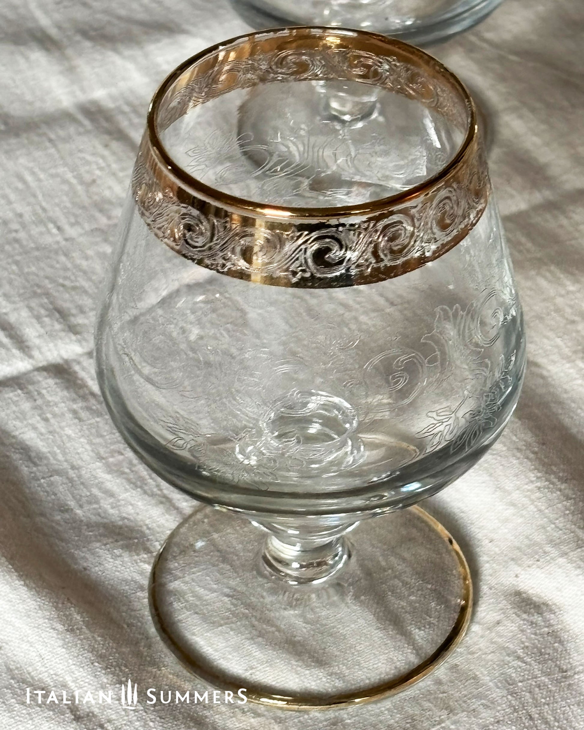 Decorative glass with gold rim on a white fabric background