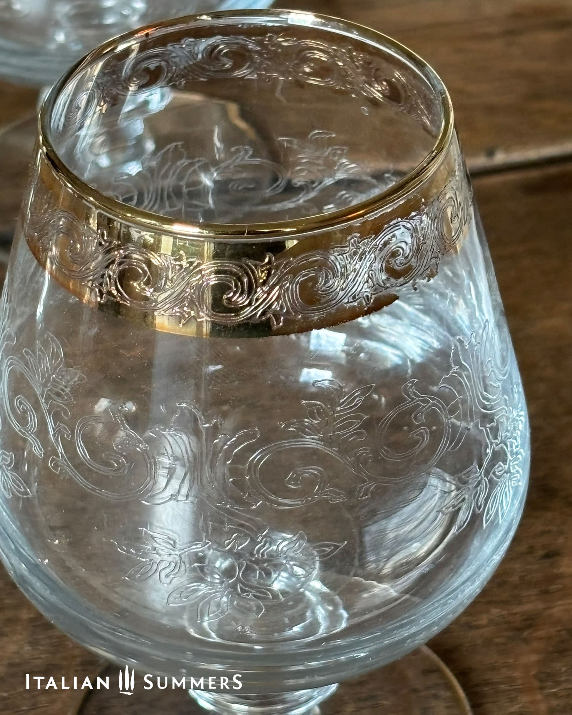 Decorative glass with gold rim on a wooden surface, branded 'Italian Summers'.