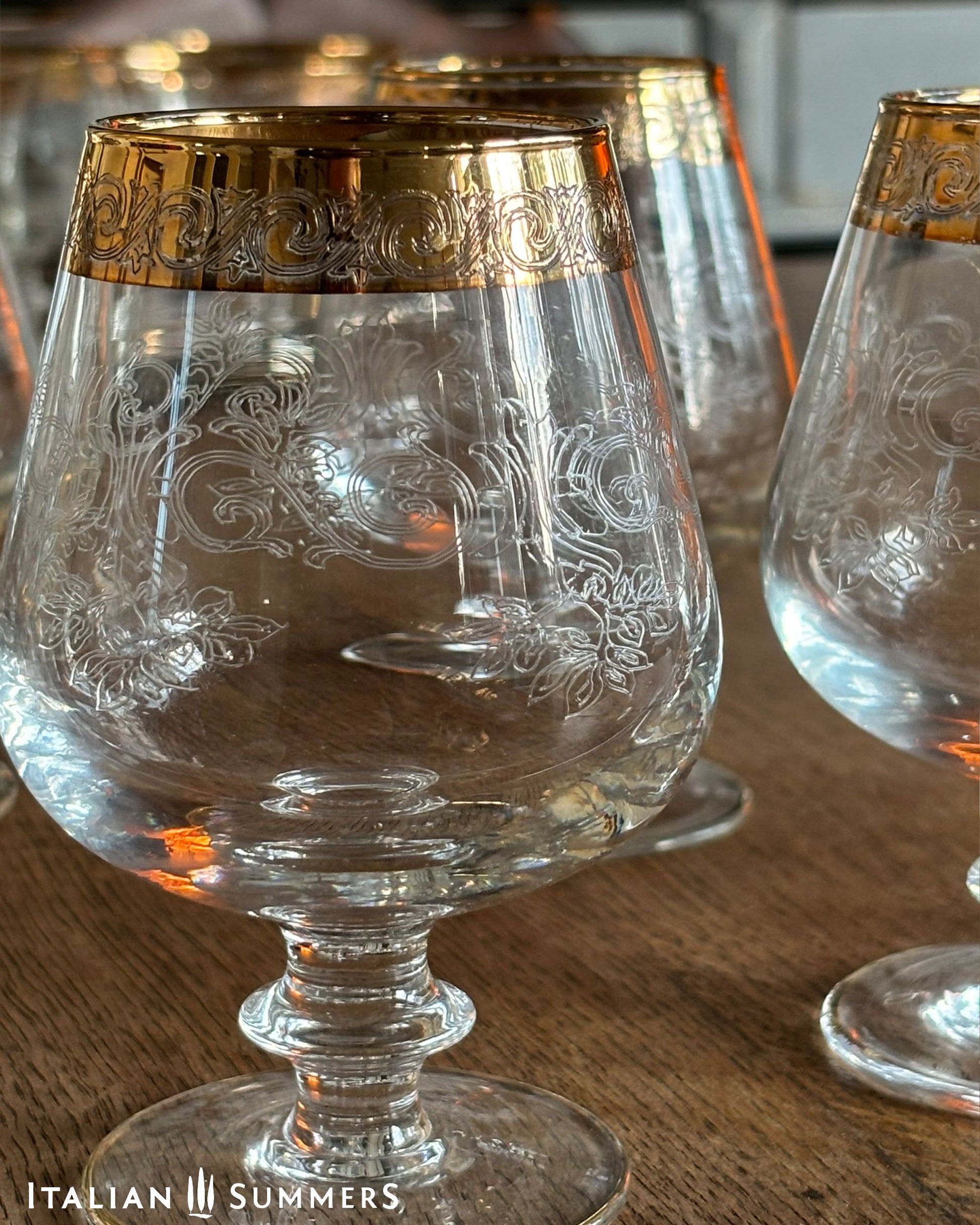 Decorative glass with gold rim on a wooden surface, featuring 'Italian Summers' branding.