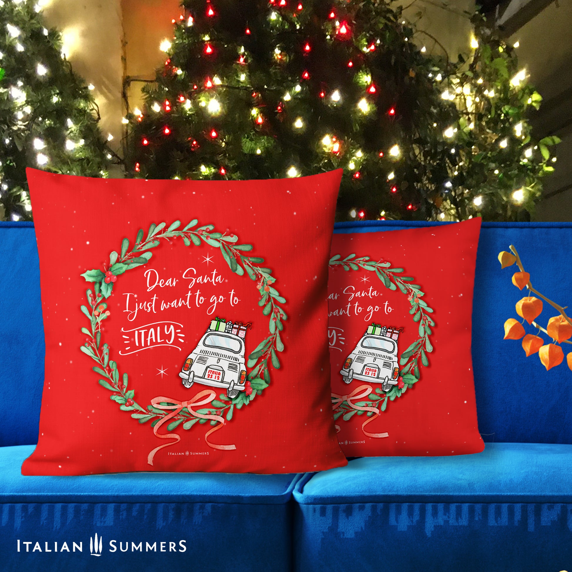 A red Italian Christmas pillow with a round Christmas wreath of green leaves an red berries. Inside the wreath there is the quote Dear Santa, I just need to go to Italy, in white text, next to the text there is the back of a driving white Cinquecento. On top of the Cinquecento there are Christmas gifts. Made by Italian Summers