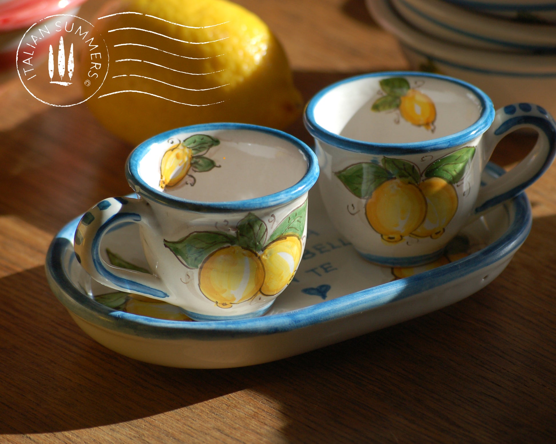 A bright and colorful Italian Maiolica ceramic espresso coffee set, two demitasse and a serving tray featuring sunny Sicilian lemons and a blue decoration with the Italian text -La vita e&#39; piu bella con te-.  hand made in Sicily