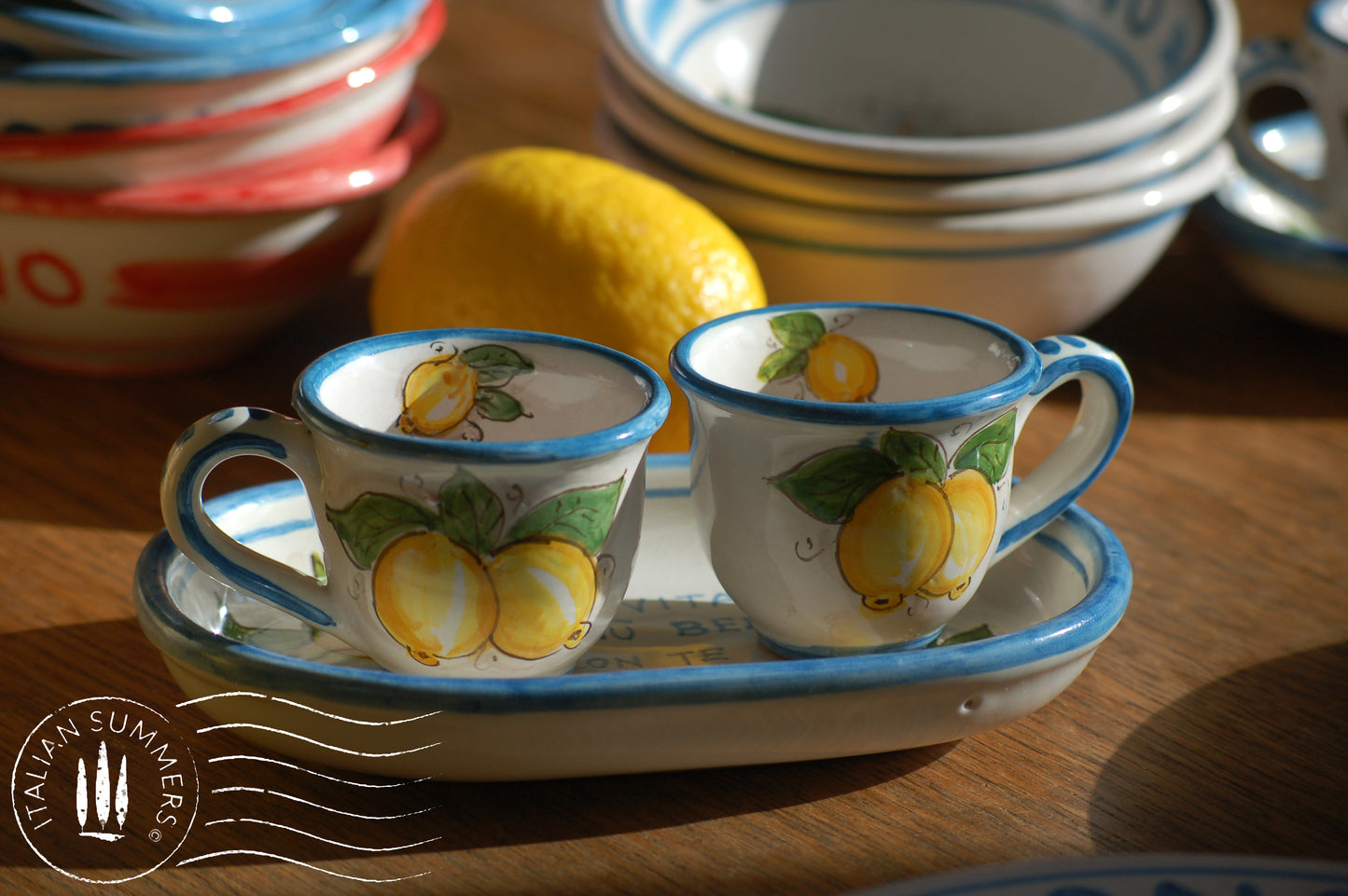 A bright and colorful Italian Maiolica ceramic espresso coffee set, two demitasse and a serving tray featuring sunny Sicilian lemons and a blue decoration with the Italian text -La vita e&#39; piu bella con te-.  hand made in Sicily