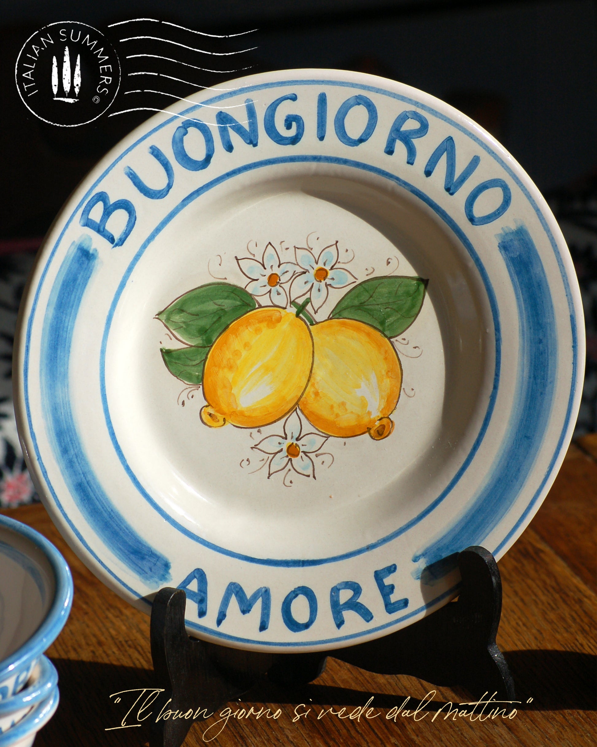 A bright and colorful Maiolica ceramic plate, hand made in Sicily featuring sunny Sicilian lemons and a blue decoration with the text, Buongiorno Amore, which means, Good Morning my Love in Italian.