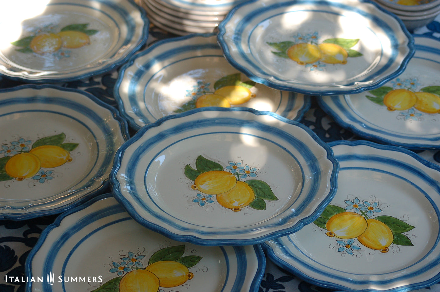 A custom made Italian maiolica ceramic dinner plate decorated with bright Sorrento Lemons and light blue stripes around the scalloped edge and in the  inside of the plate framing the lemons. 