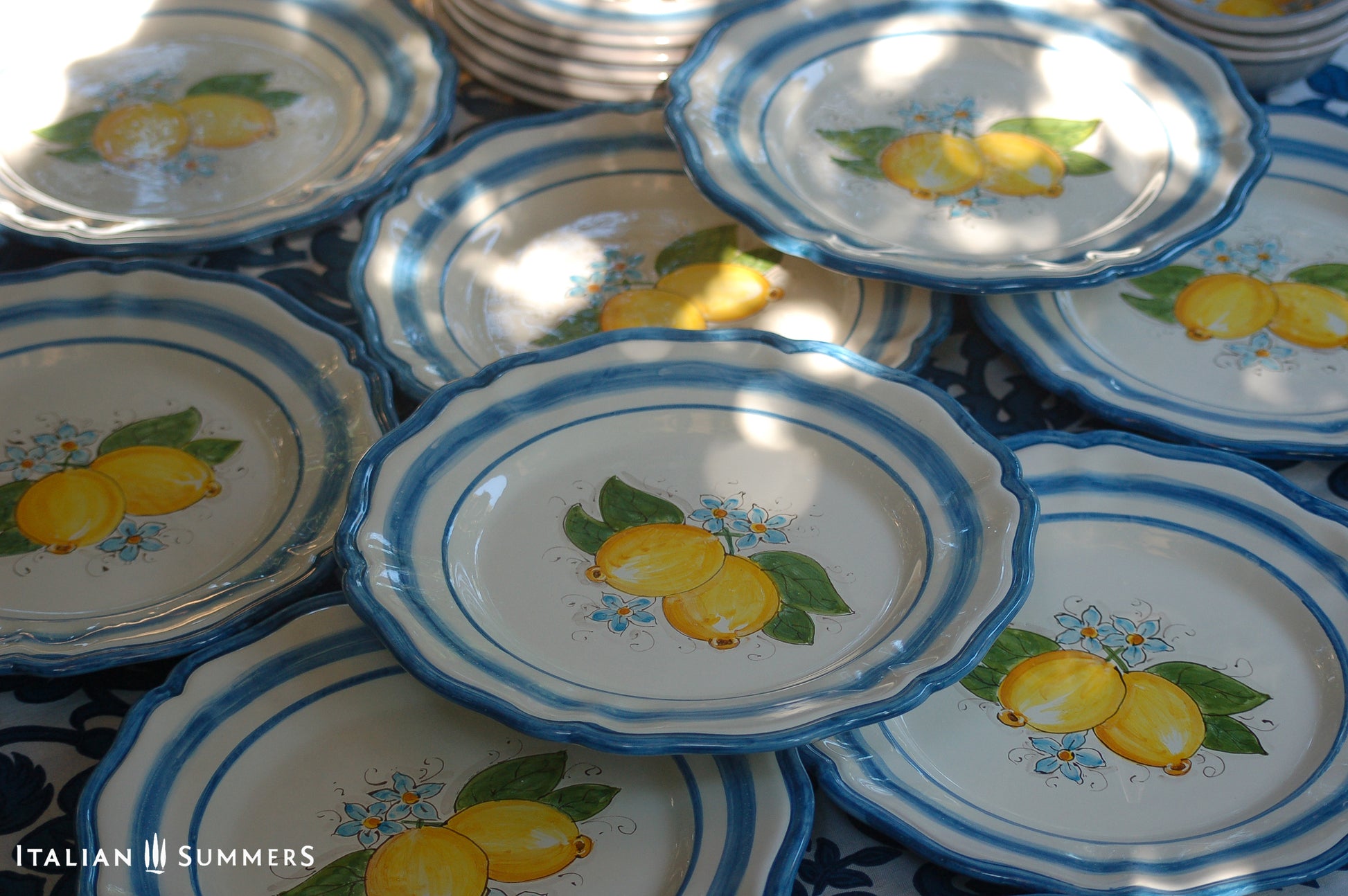 A custom made Italian maiolica ceramic dinner plate decorated with bright Sorrento Lemons and light blue stripes around the scalloped edge and in the  inside of the plate framing the lemons. 