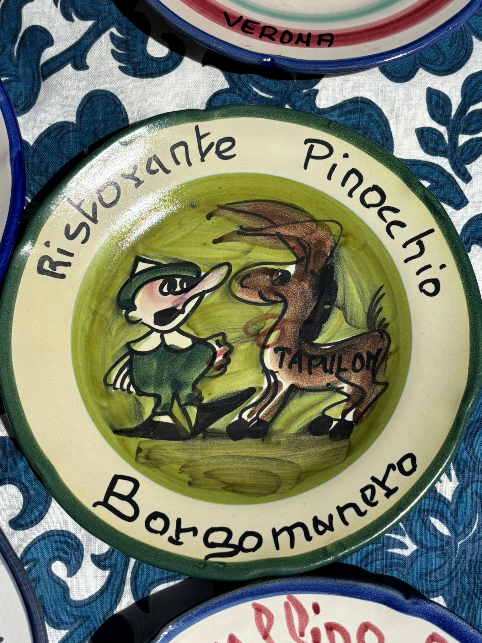 Italian ceramic plate with illustrations of Pinocchio and a donkey,with the text Ristorante Pinocchio, Borgomanero