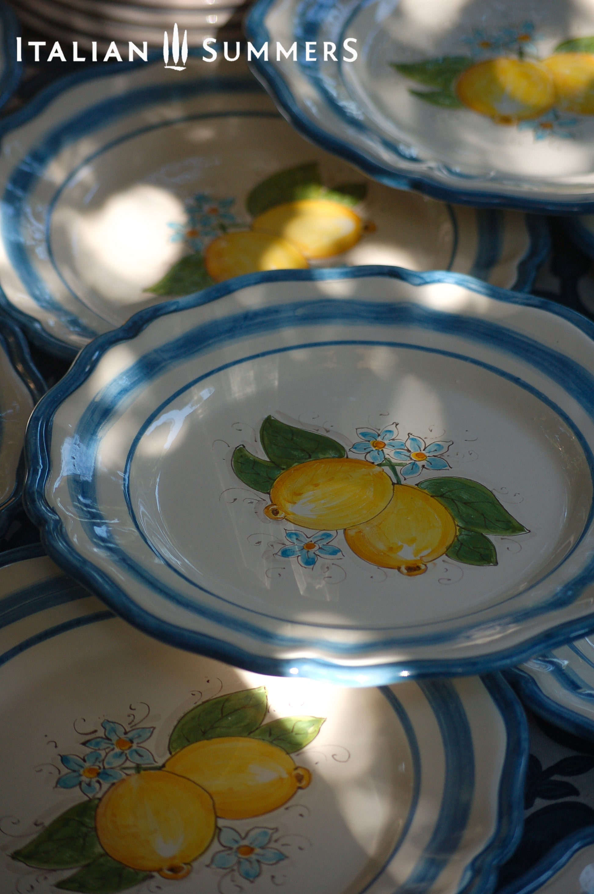 A custom made Italian maiolica ceramic dinner plate decorated with bright Sorrento Lemons and light blue stripes around the scalloped edge and in the  inside of the plate framing the lemons. 