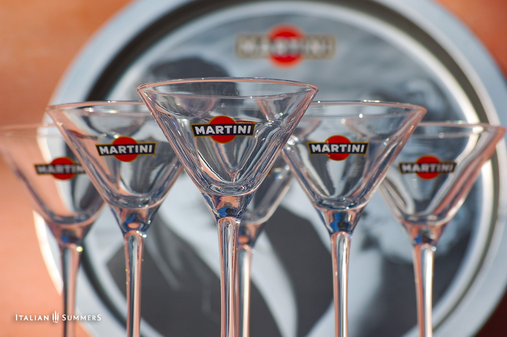 Set of Martini brand martini glasses in front of a Martini bottle.