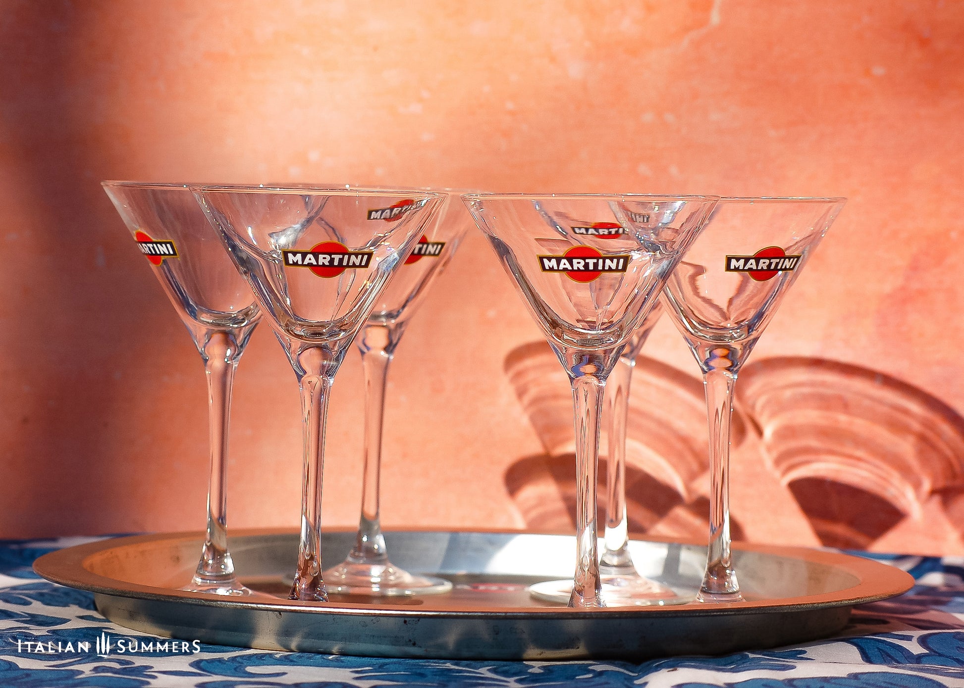 Four Martini glasses on a silver tray with a warm-toned background