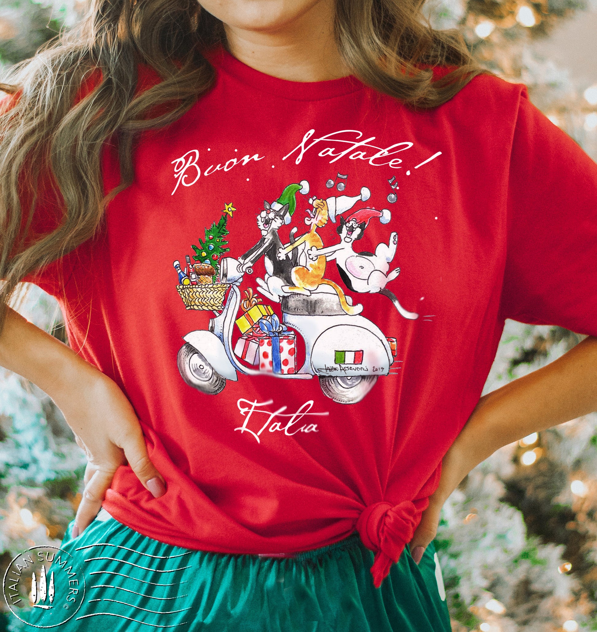A girl is wearing a red T Shirt with a happy print of a drawing of three Italian cats riding a vintage white Vespa scooter and singing  "Buon Natale!"  - Merry Christmas In Italian.