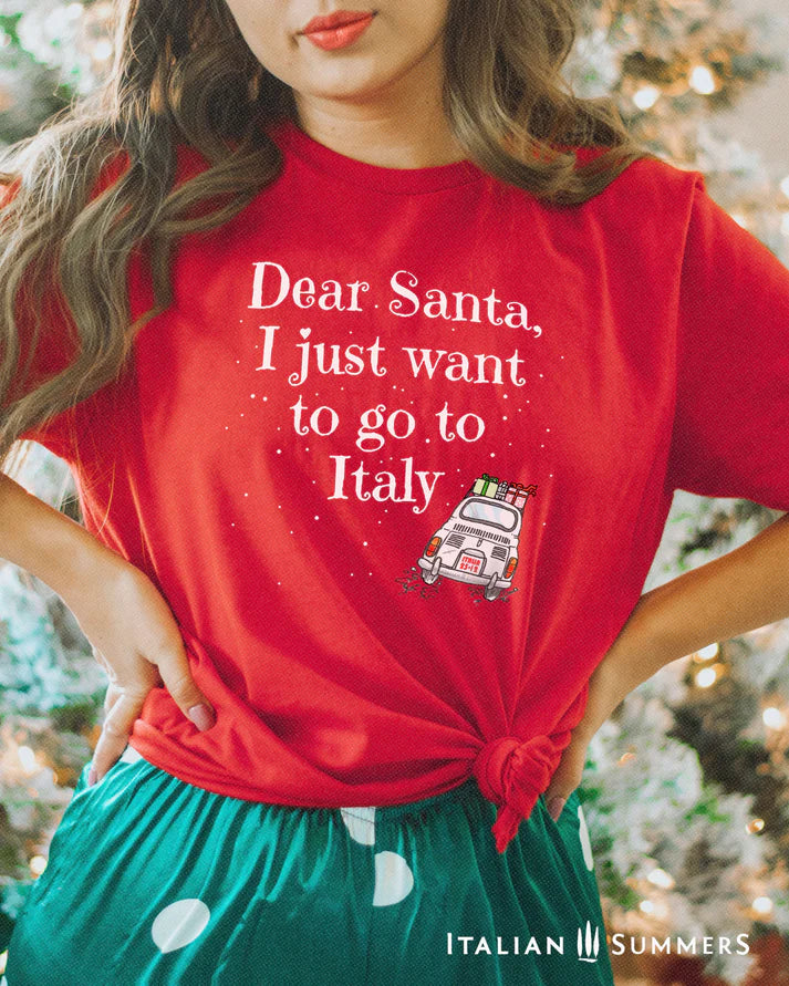 Italy Christmas red T shirt featuring a cute vintage Fiat car loaded with gifts and driving away in the snow. A large text states: " Dear Santa  I just want to go to Italy"