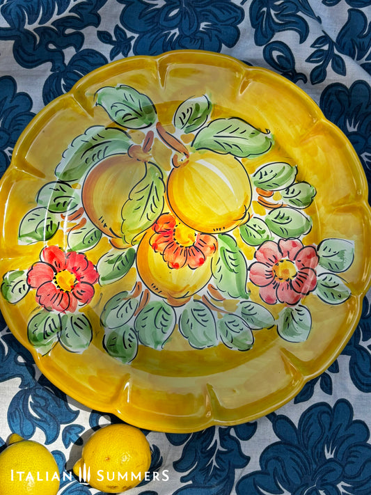 Italian Vietri Decorative ceramic plate with lemon design on a floral patterned fabric background

