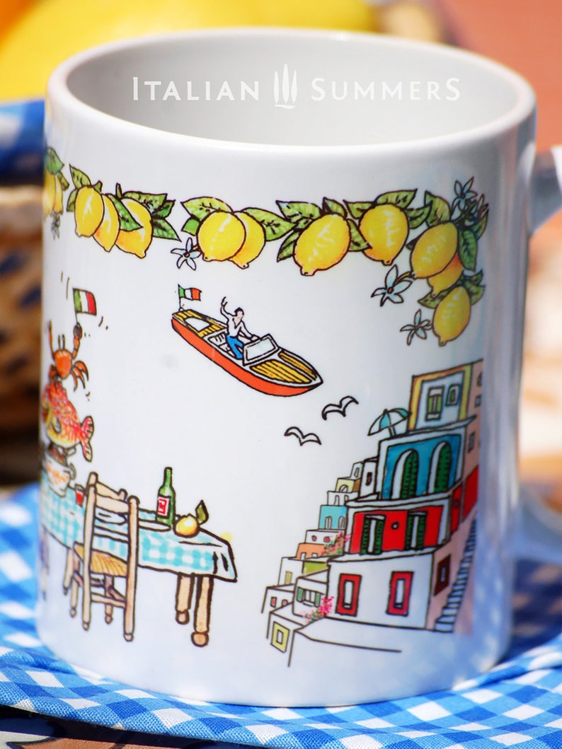 Italy | Amalfi Coast inspired mug with sketches that refer to the Amalfi Coast | Positano. There is a light blue vintage Cinquecento cabrio with a man and a woman seen from the back, the colorful houses of the Amalfi coast, a long table with a blue checkered table cloth, lemons, wine, a smiling fish and a crab with an Italian flag. On the rim there is a lemon garland and in the middle the red writing Amalfi coast. A really happy mug! Made by Italian Summers