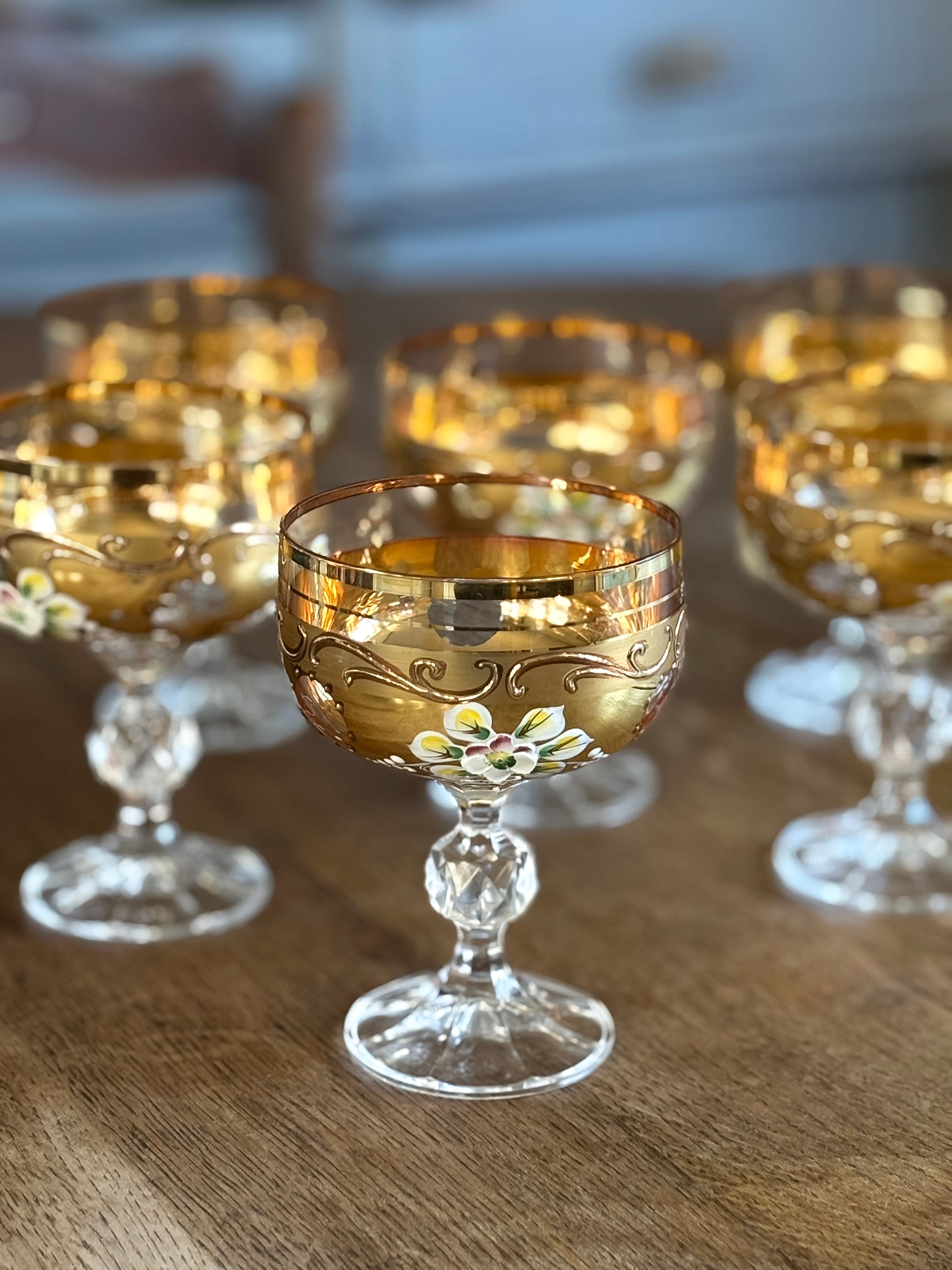 Set of gold-rimmed glass goblets on a wooden surface