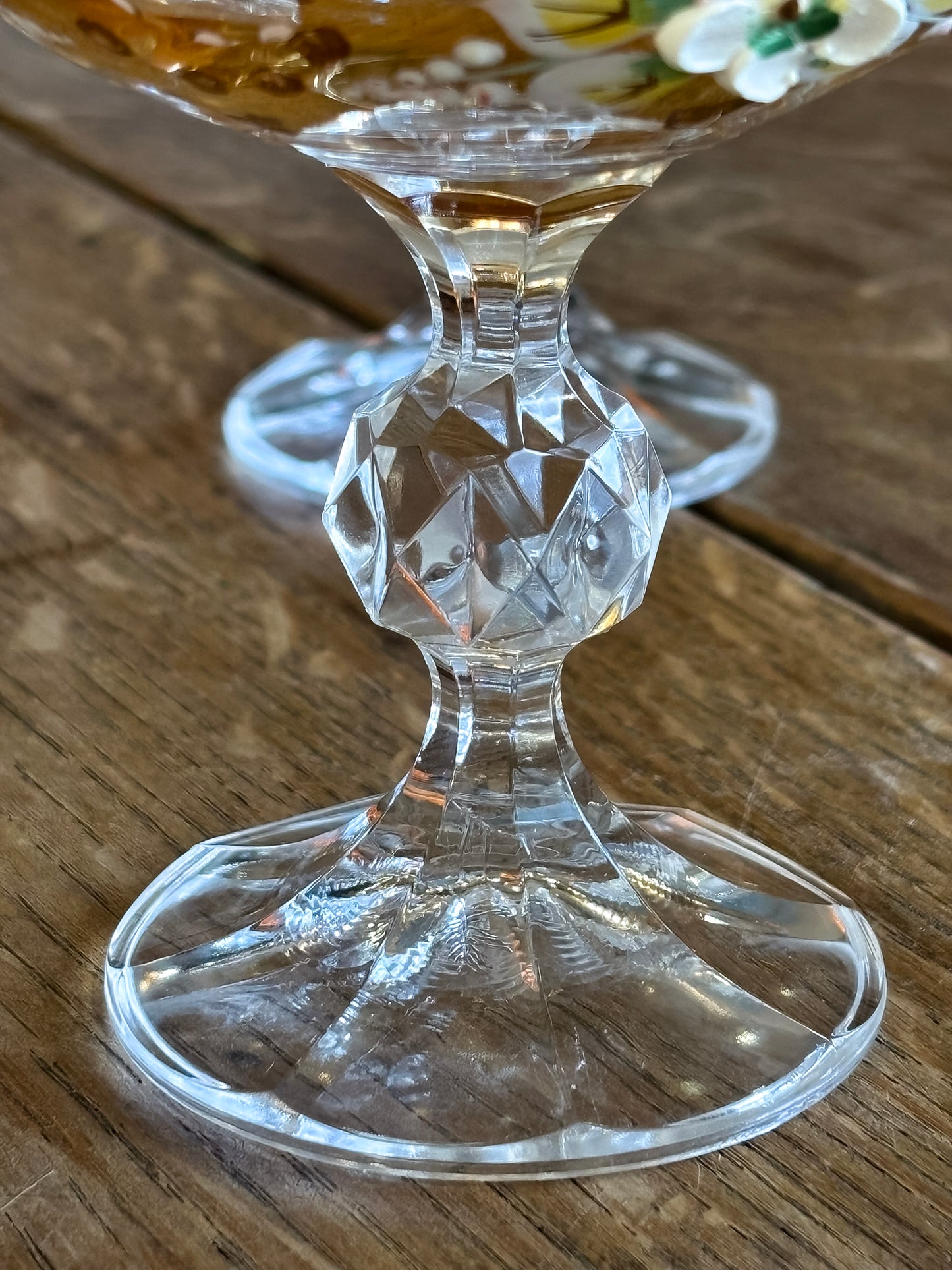 Deatil of a crystal Murano  wine goblet with intricate design on a wooden surface
