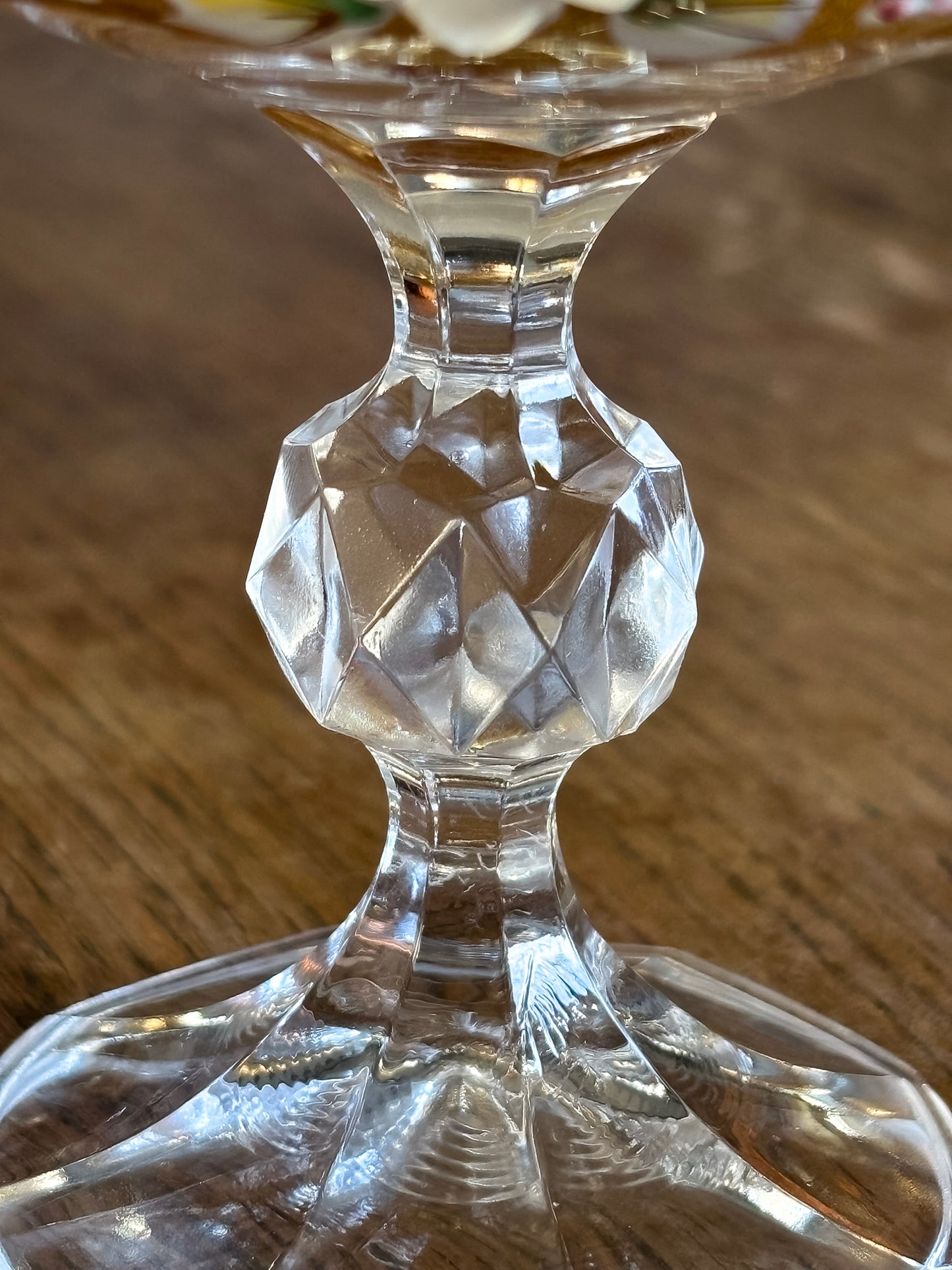 Close-up of a clear crystal faceted stem  of a decorative goblet on a wooden surface