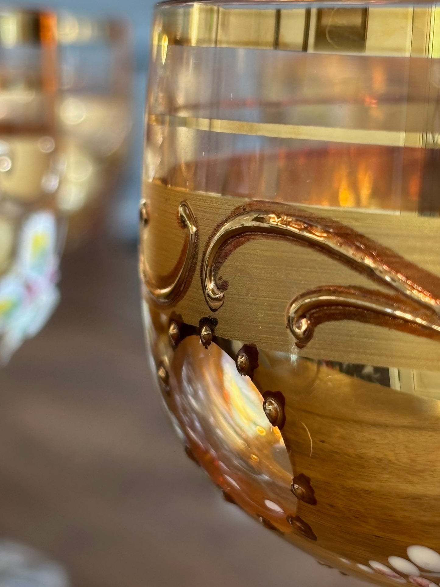 Close-up of a decorative glass with gold accents and a blurred background