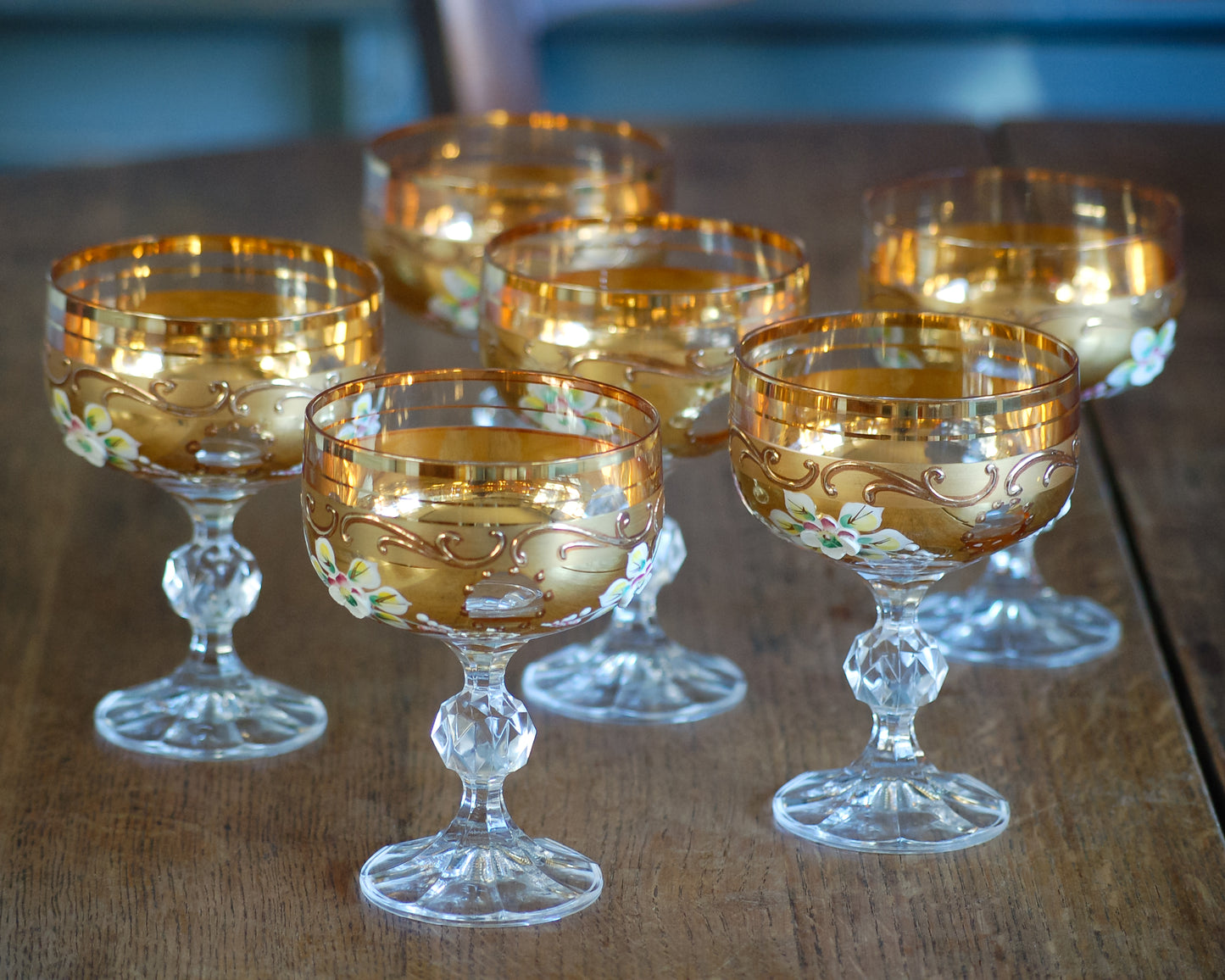 Set of ornate Murano glass goblets with gold decotation on a wooden table