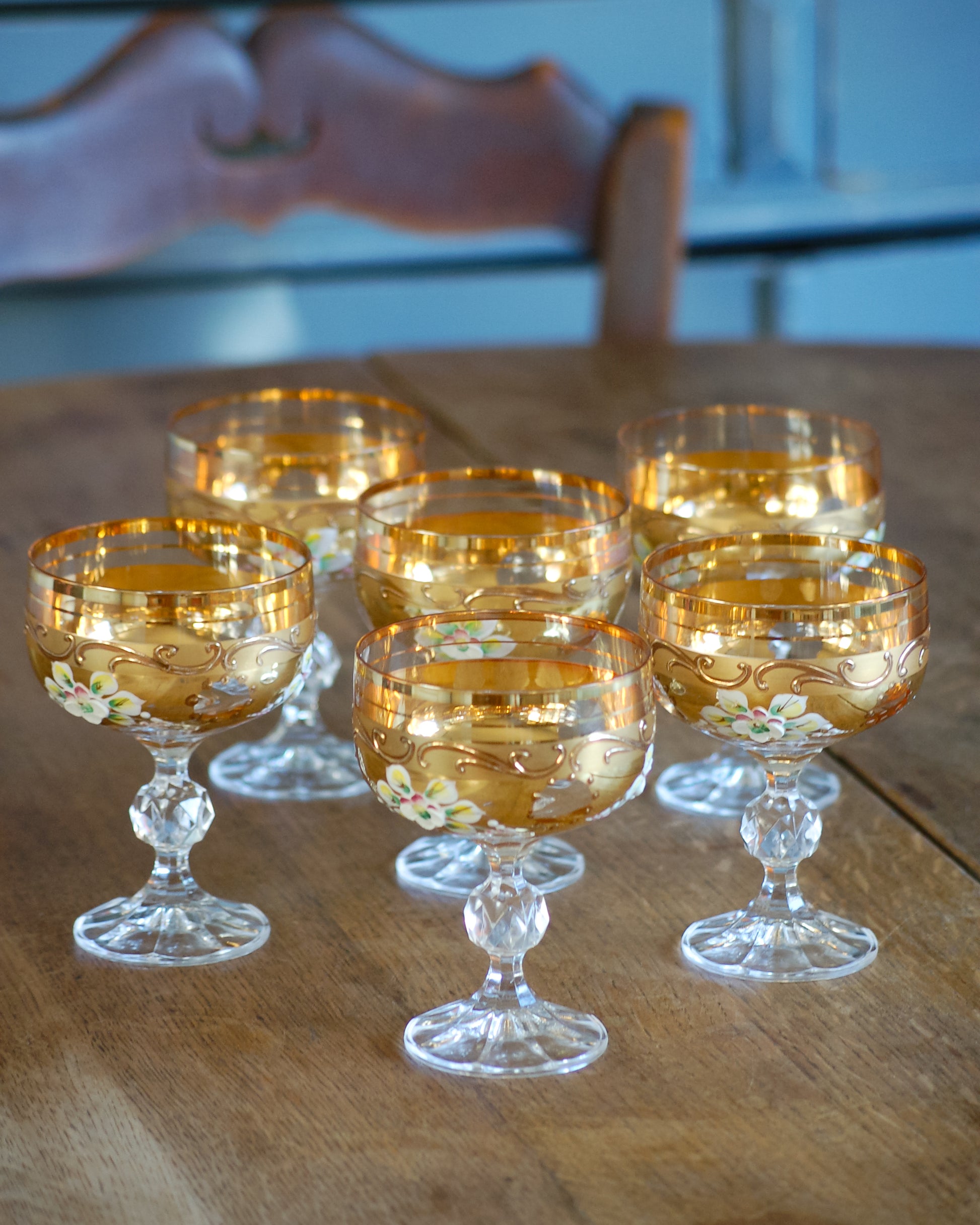 Set of six gold-rimmed glass Murano wine  goblets on a wooden table