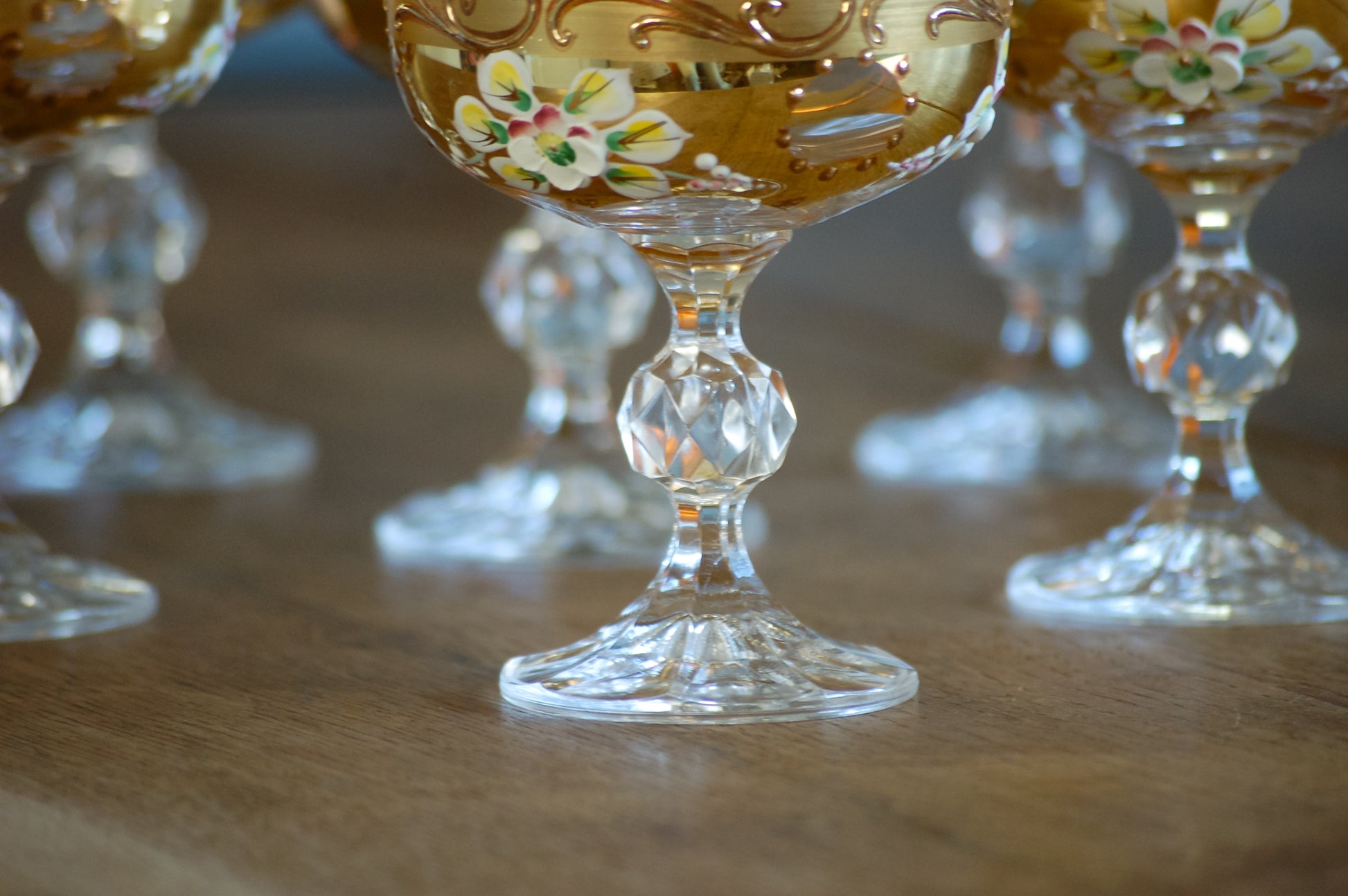 Decorative glass goblets with floral designs on a wooden surface